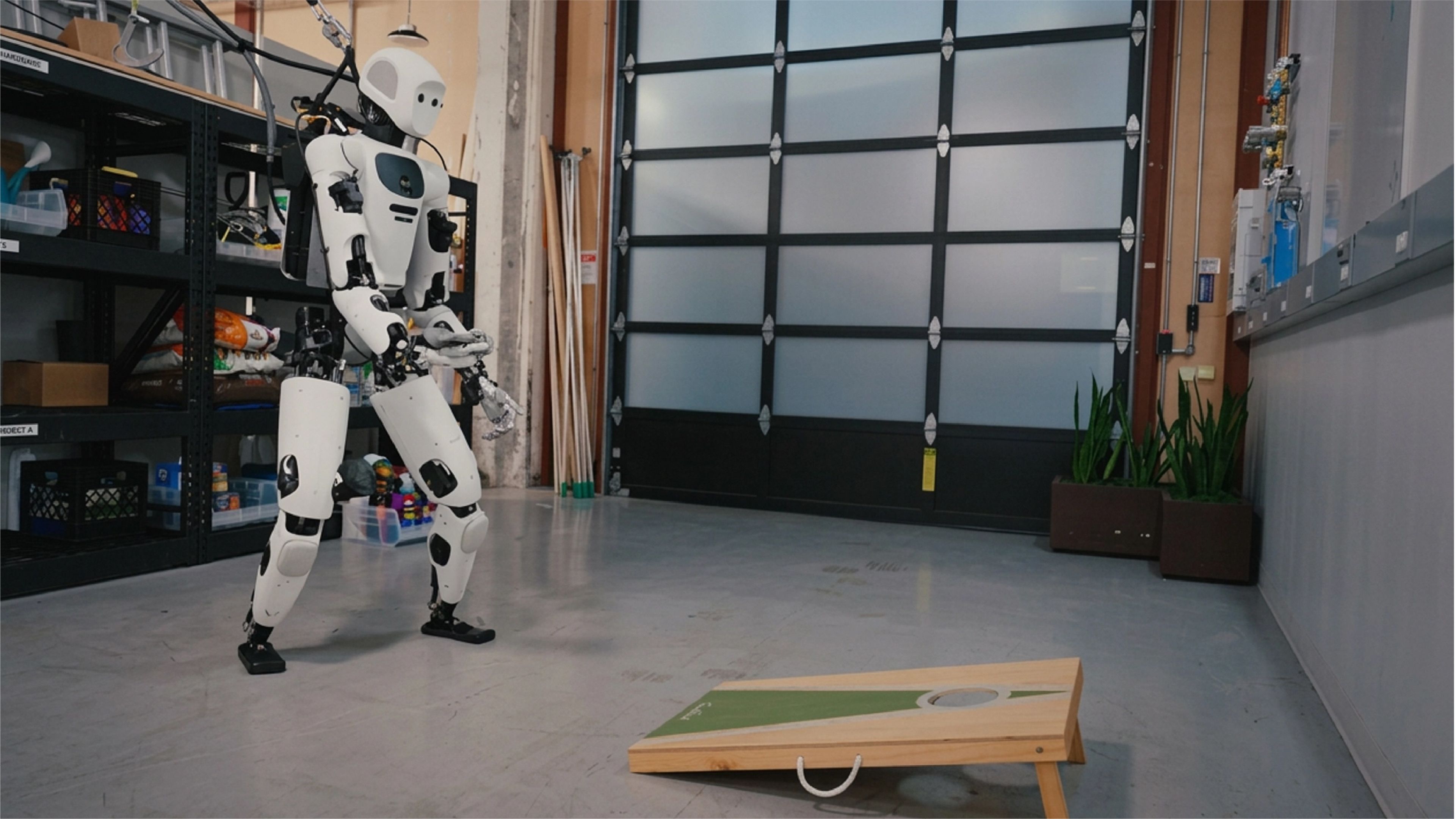 A humanoid robot prepares to throw a beanbag at a cornhole board inside a robotics laboratory.
