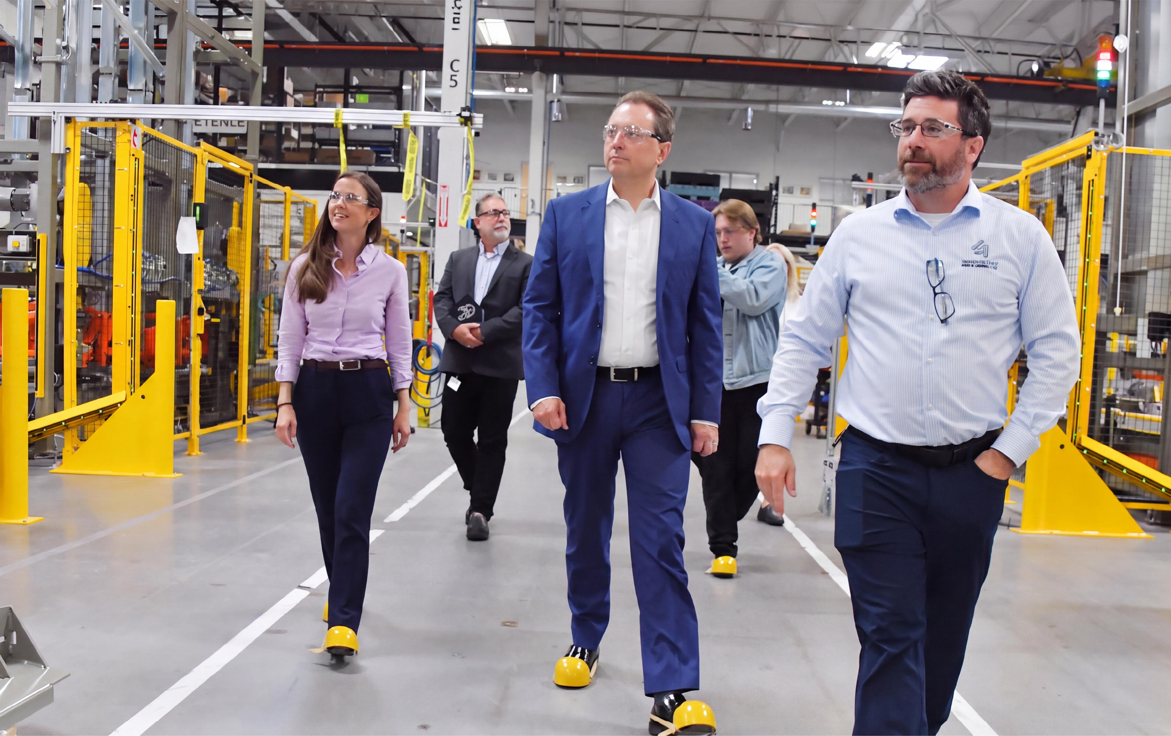 Visitors tour an advanced manufacturing facility equipped with automated machinery and industrial safety systems.
