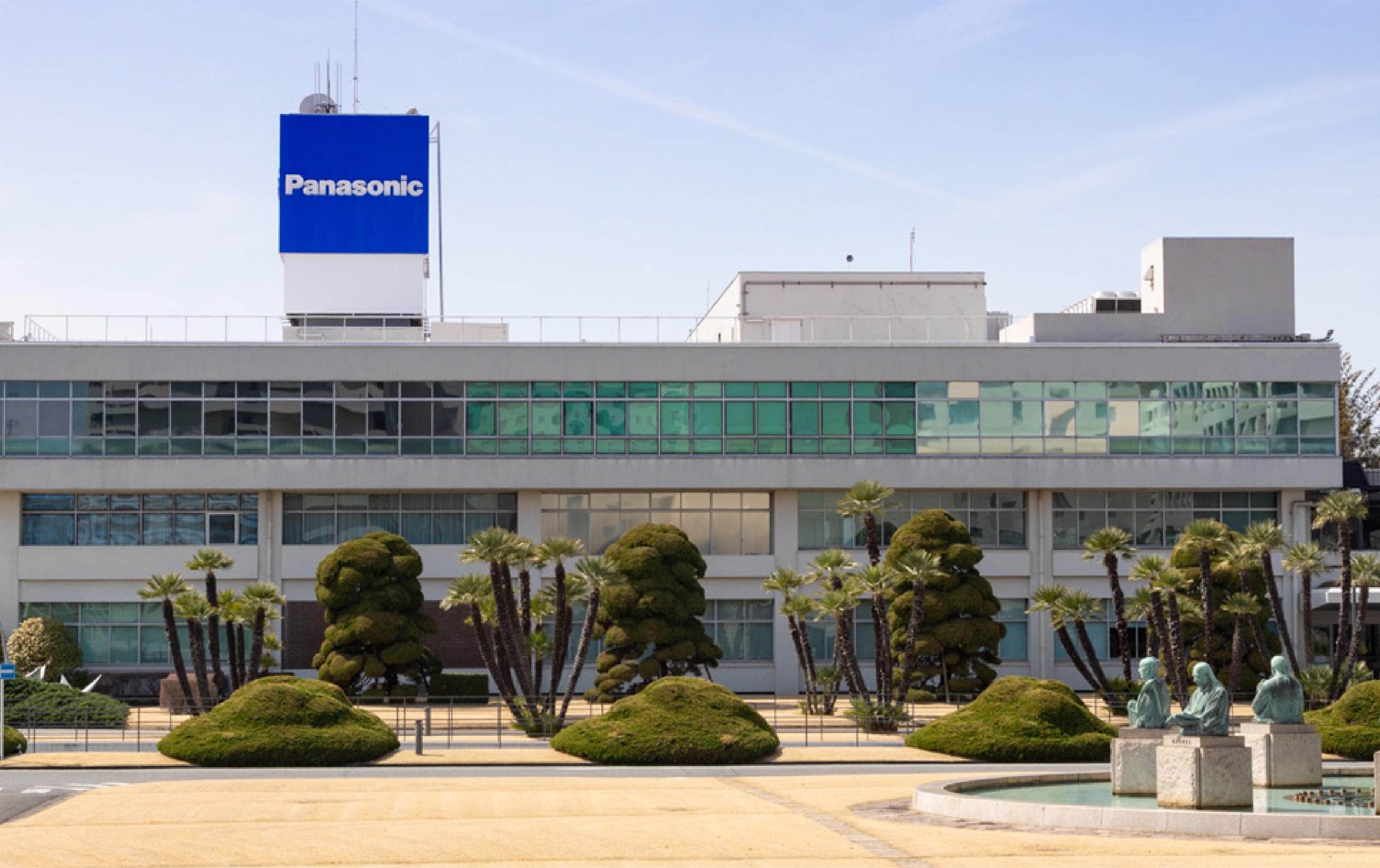 Panasonic building with the company’s blue logo displayed above landscaped grounds and a fountain.