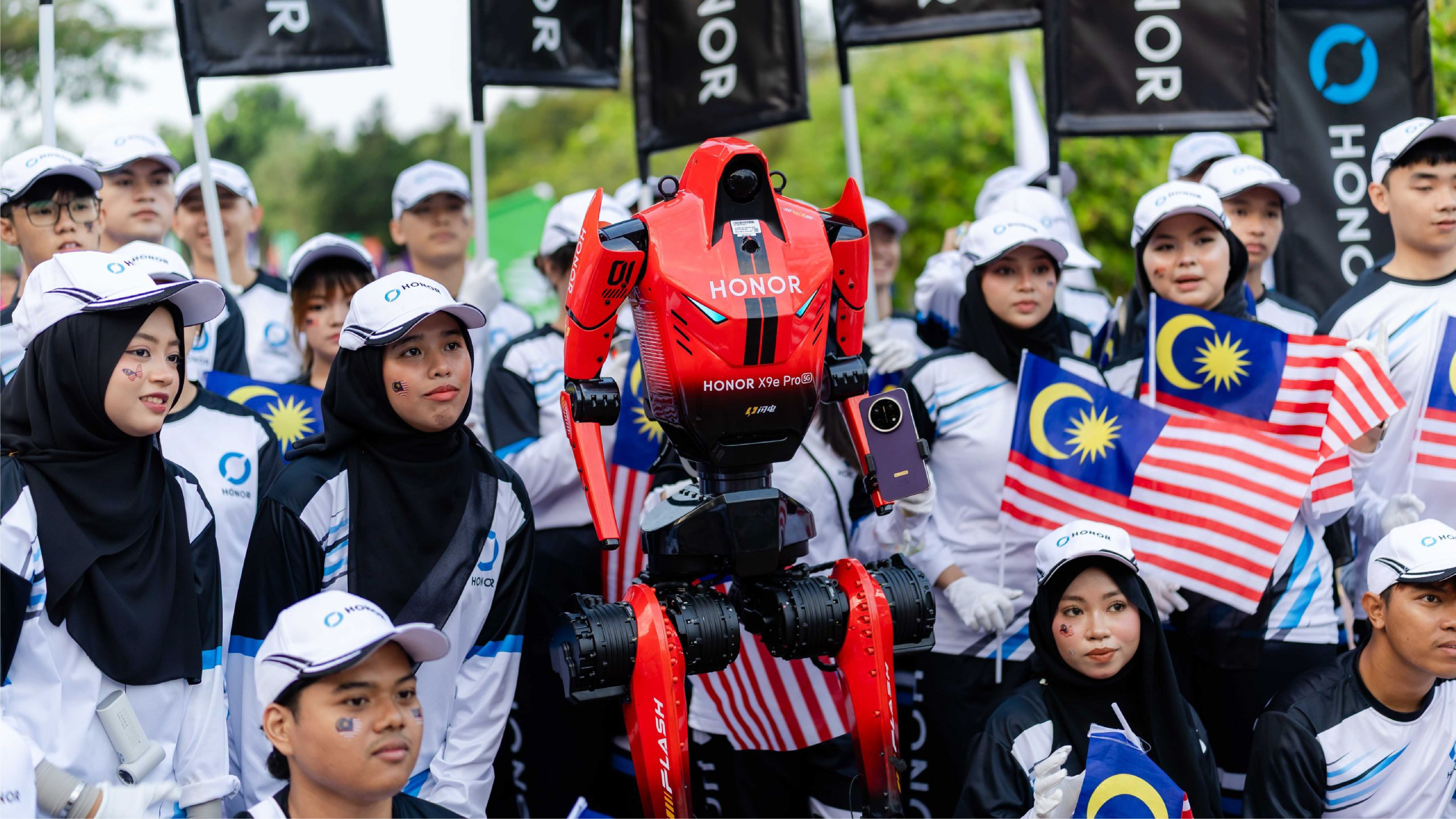 HONOR’s D1 humanoid robot stands among people holding Malaysian flags at a public event in Kuala Lumpur.