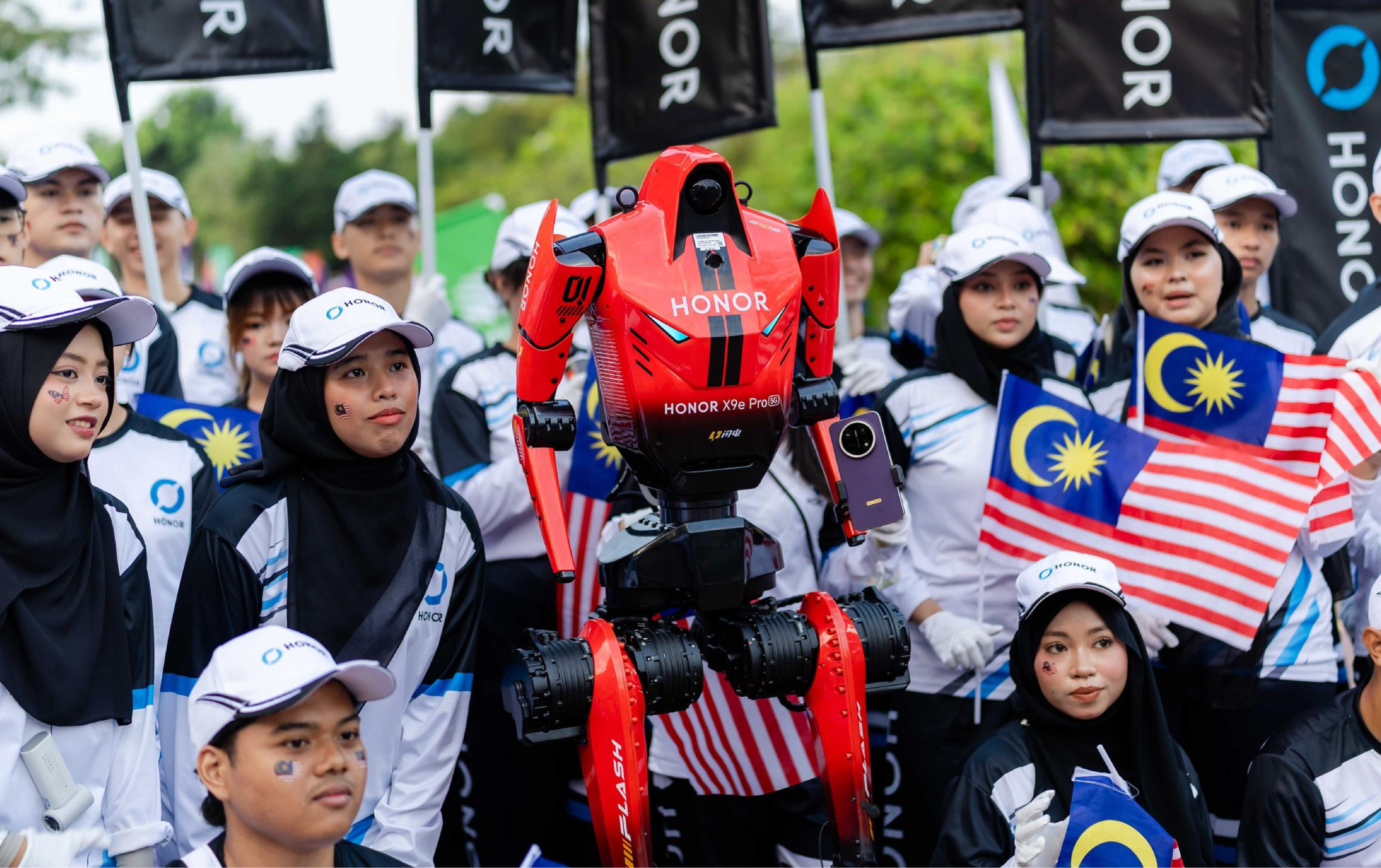 HONOR’s D1 humanoid robot stands among people holding Malaysian flags at a public event in Kuala Lumpur.