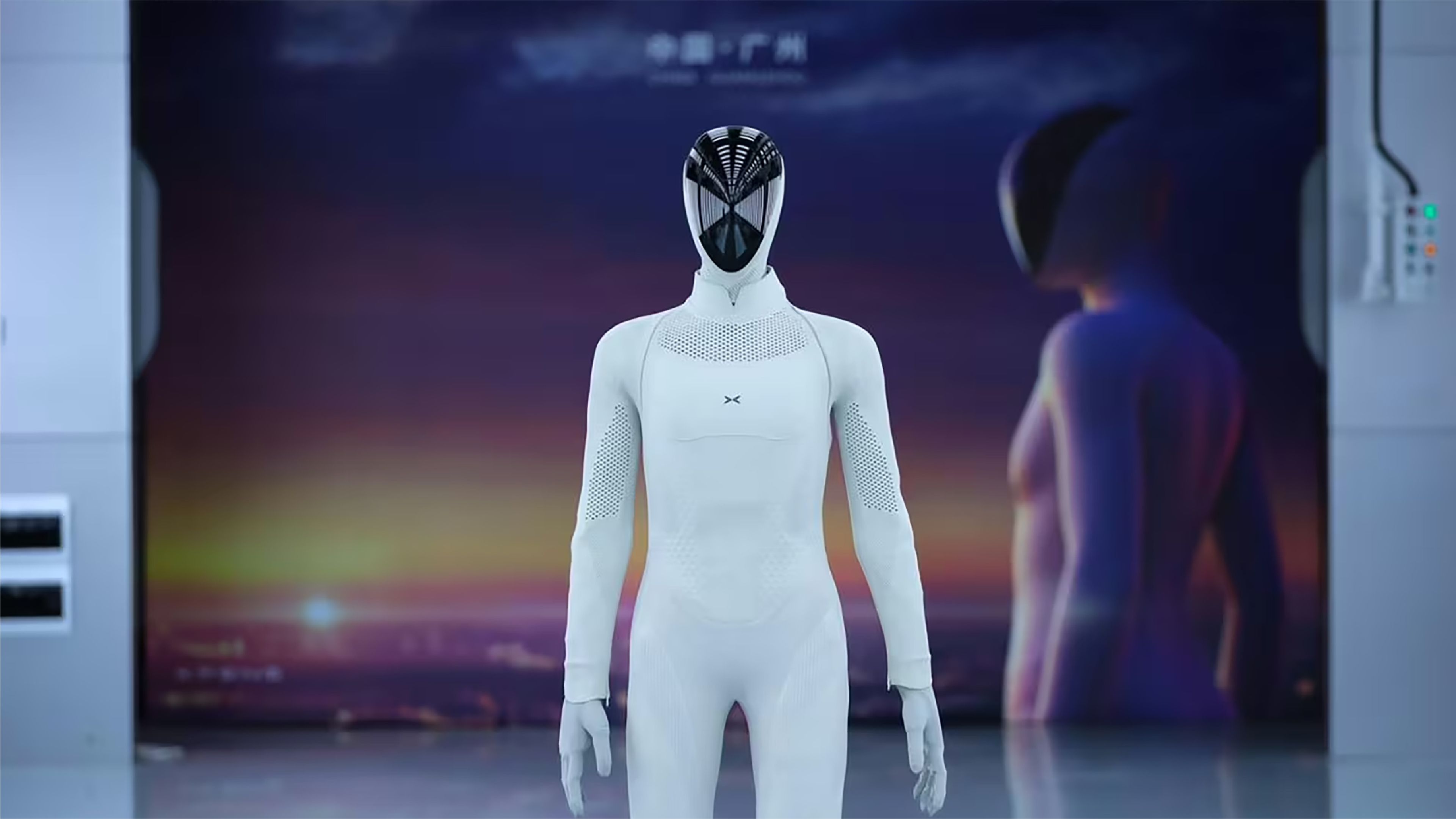 XPeng’s humanoid robot stands on a production line as a worker looks on.