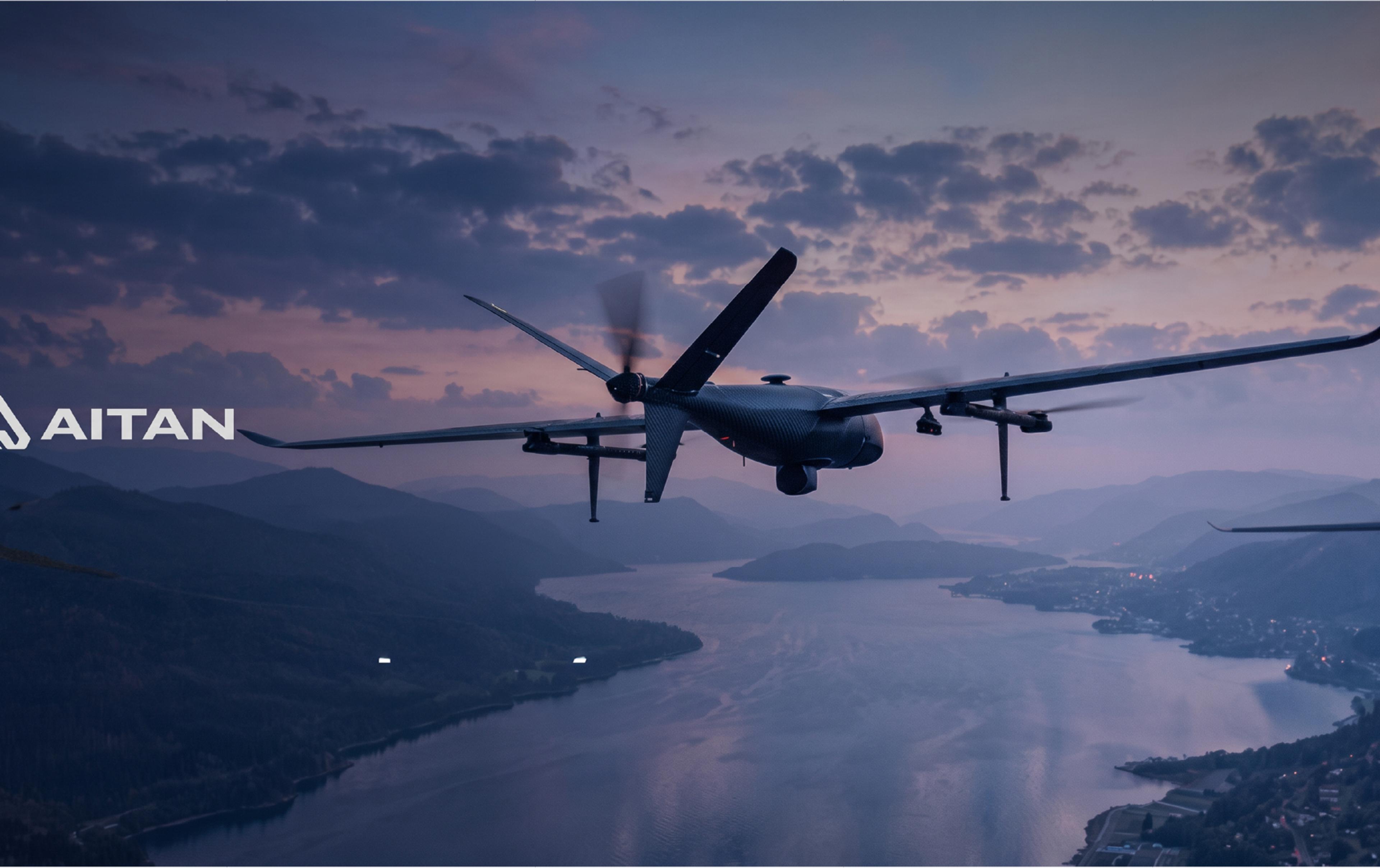 Aitan military drone flying over a mountainous landscape and lake at dusk, with the Aitan logo displayed on the left.