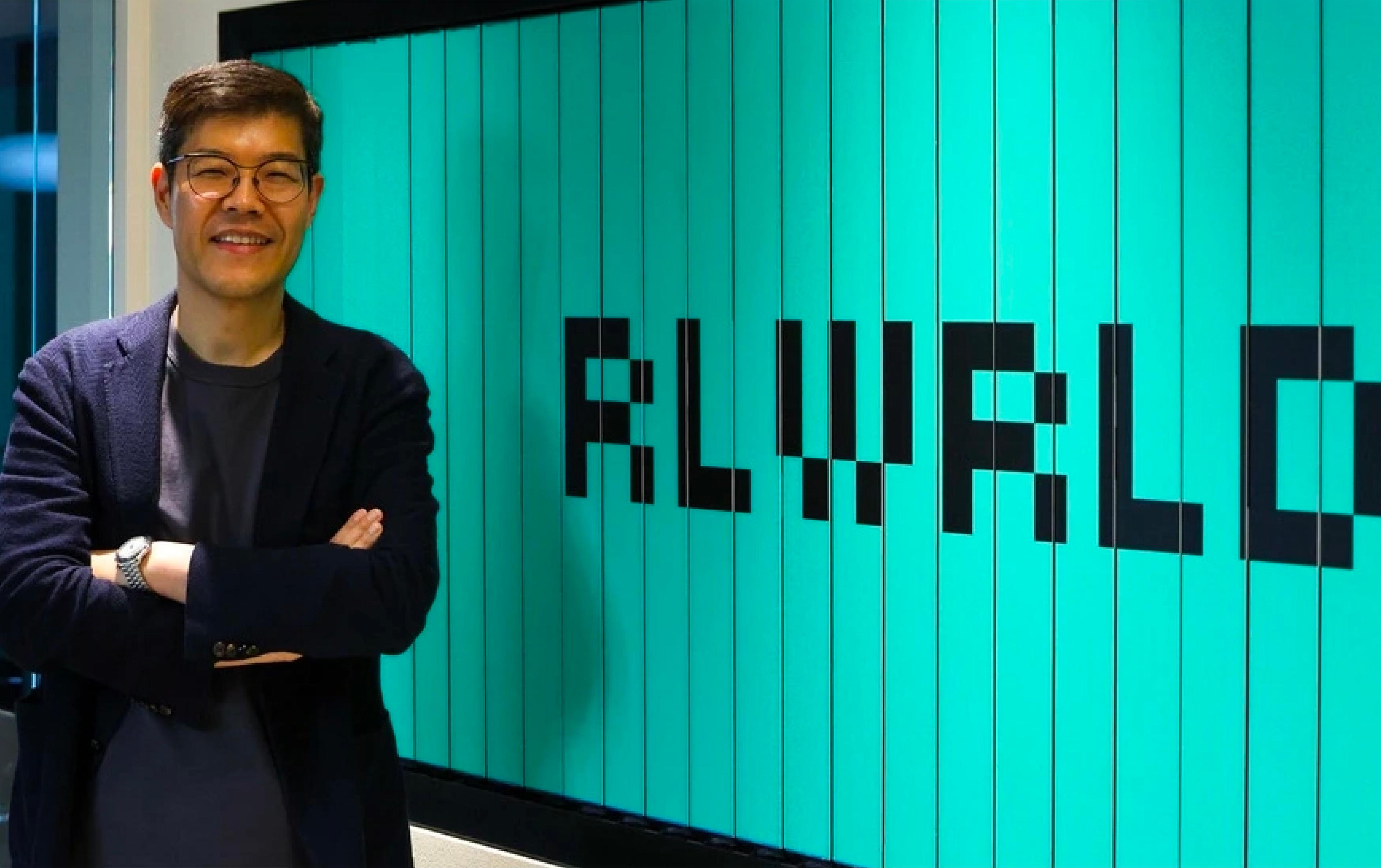 RLWRLD founder and CEO Junghee Ryu stands beside a large RLWRLD logo display.