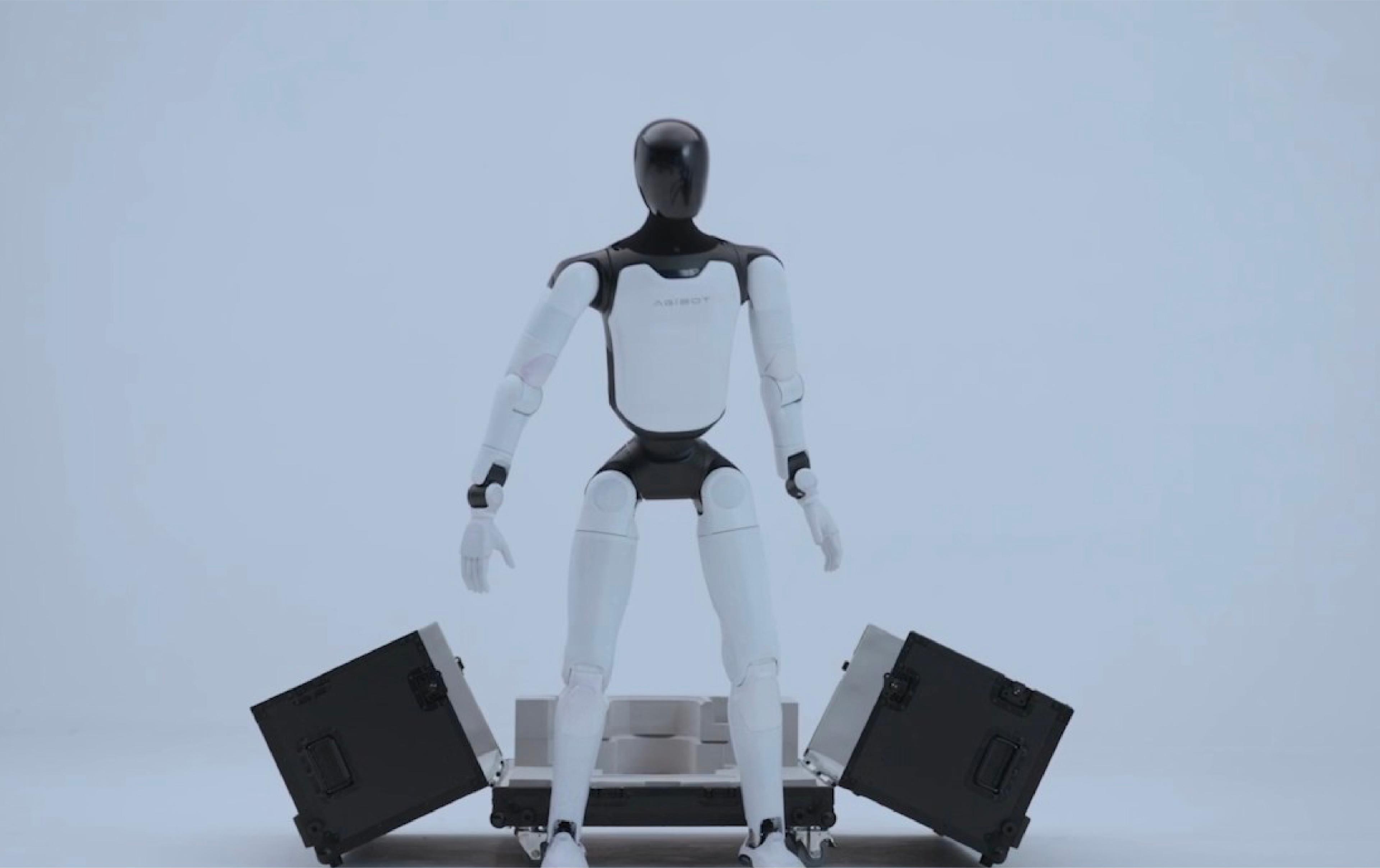 A robotic arm holds a box and a green object, showcasing its precision and versatility in handling various items.