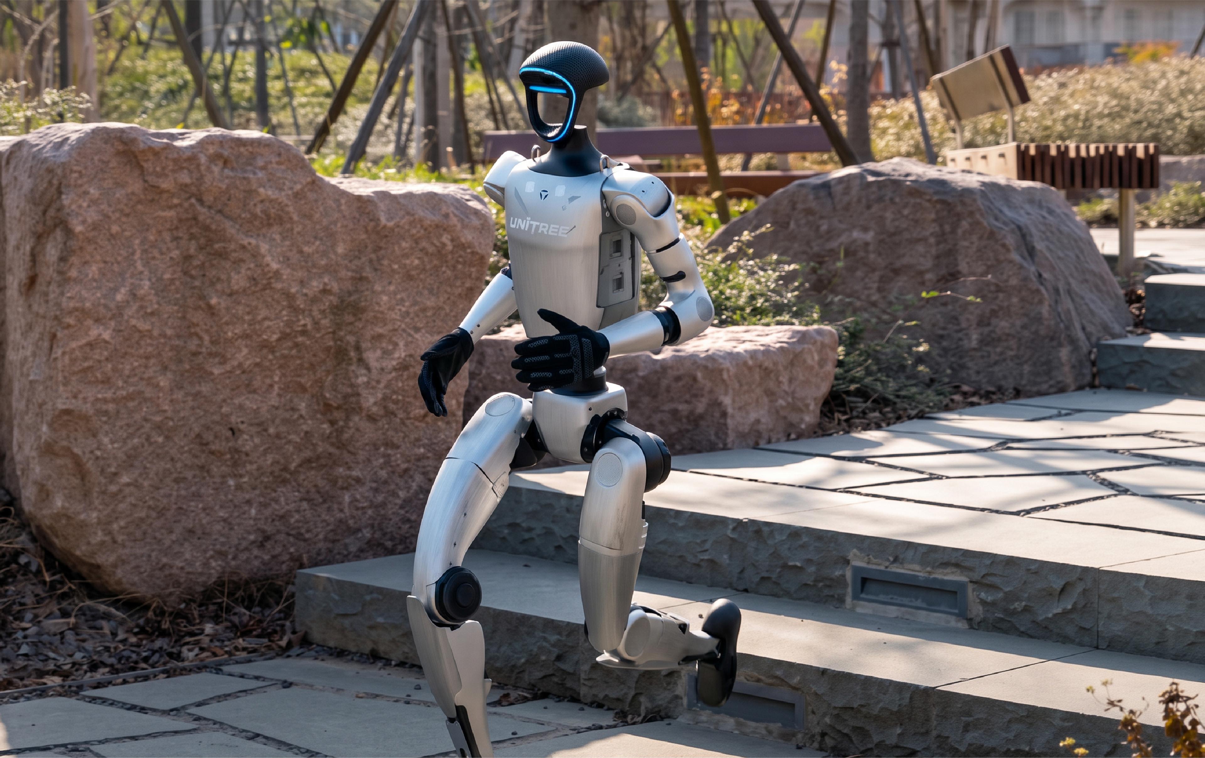 A Unitree humanoid robot walks down stone steps in an outdoor park.