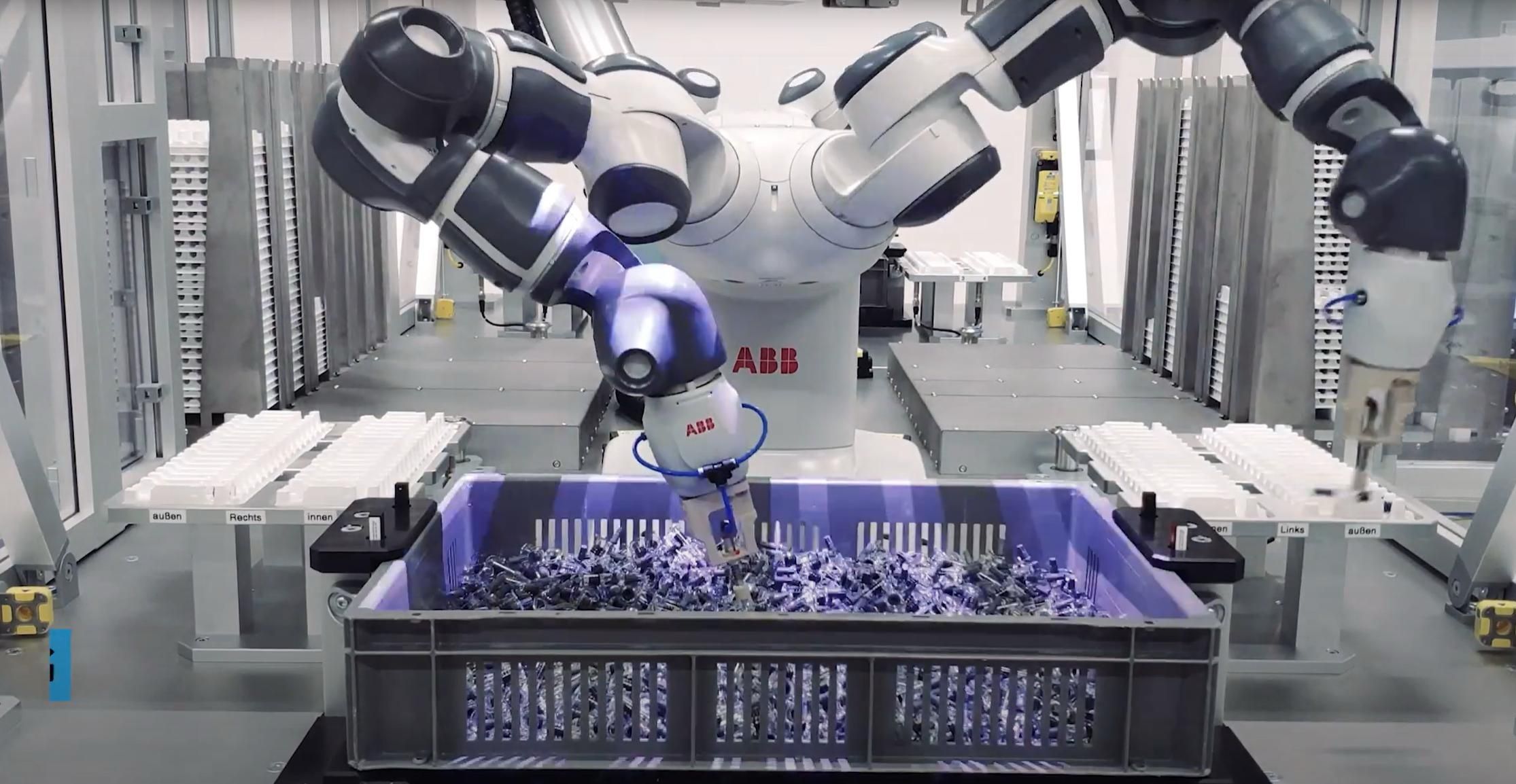 A robot operates a machine in a factory setting, showcasing automation in industrial processes.