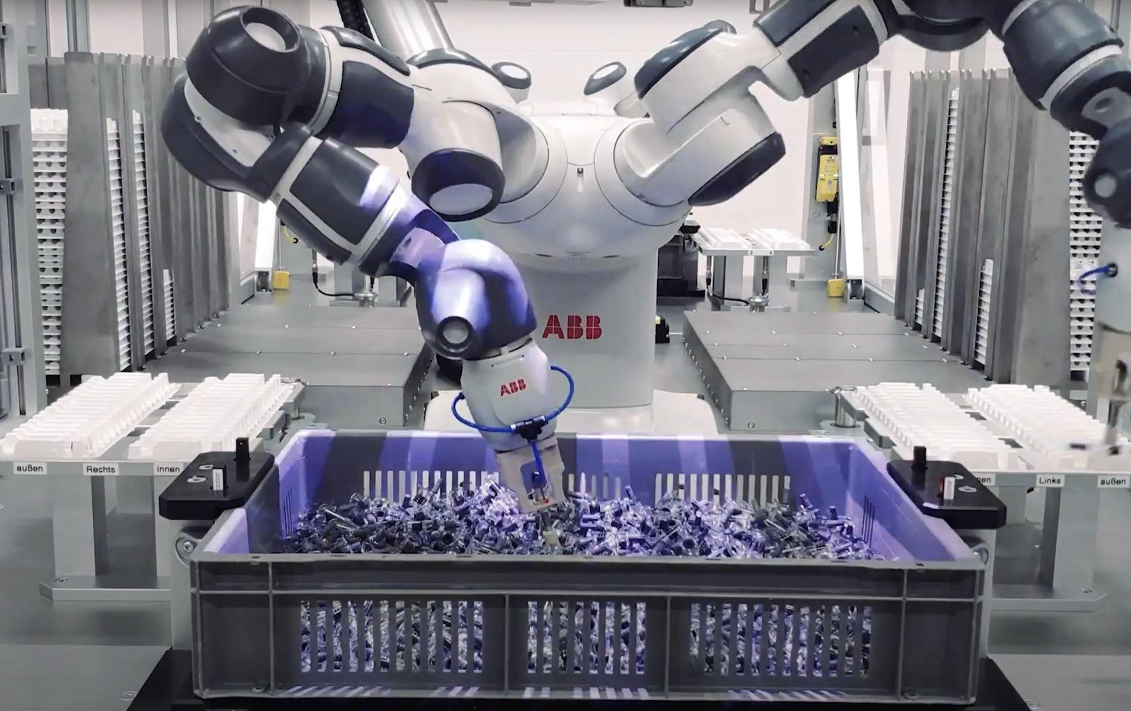 A robot operates a machine in a factory setting, showcasing automation in industrial processes.