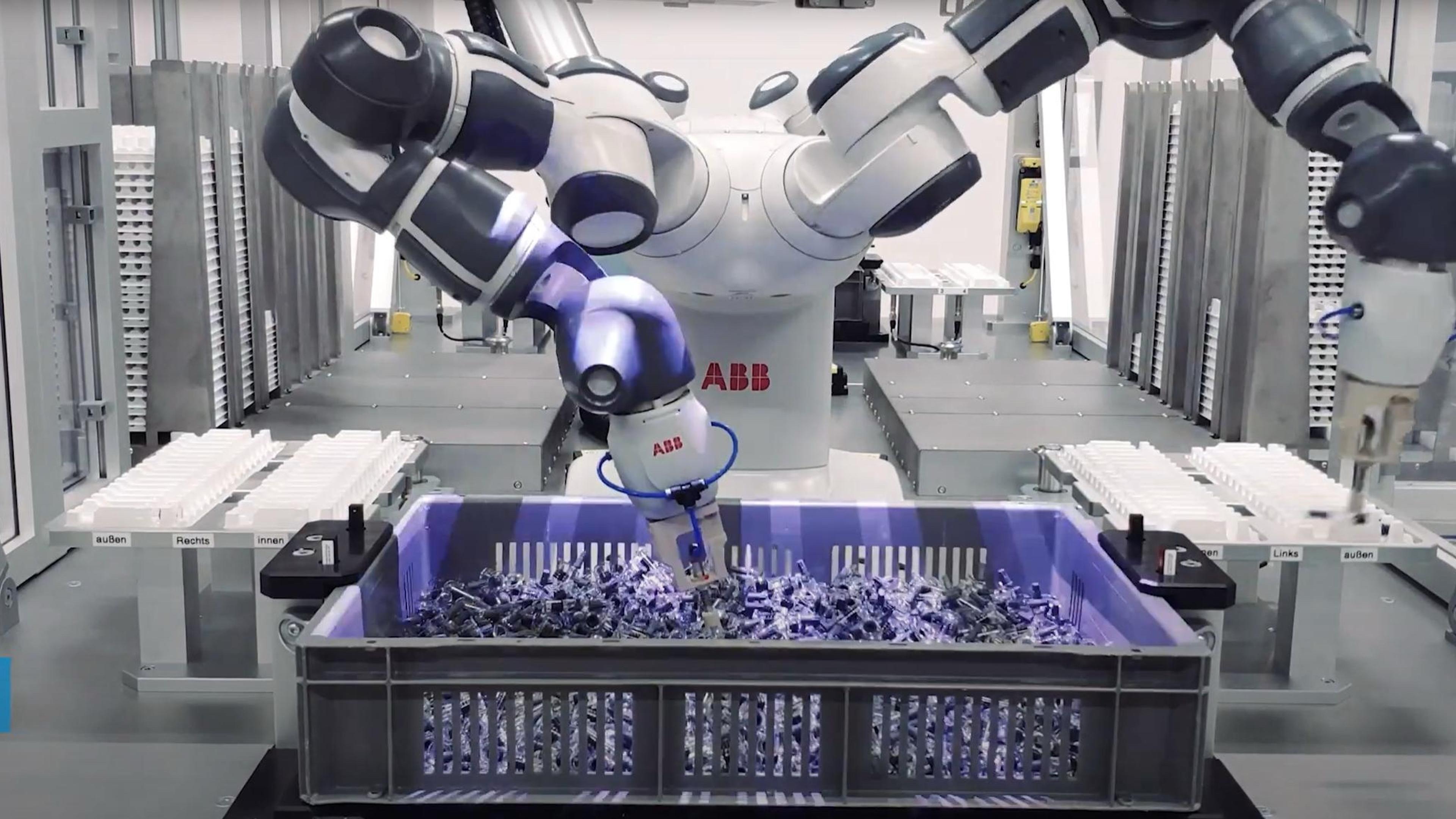 A robot operates a machine in a factory setting, showcasing automation in industrial processes.