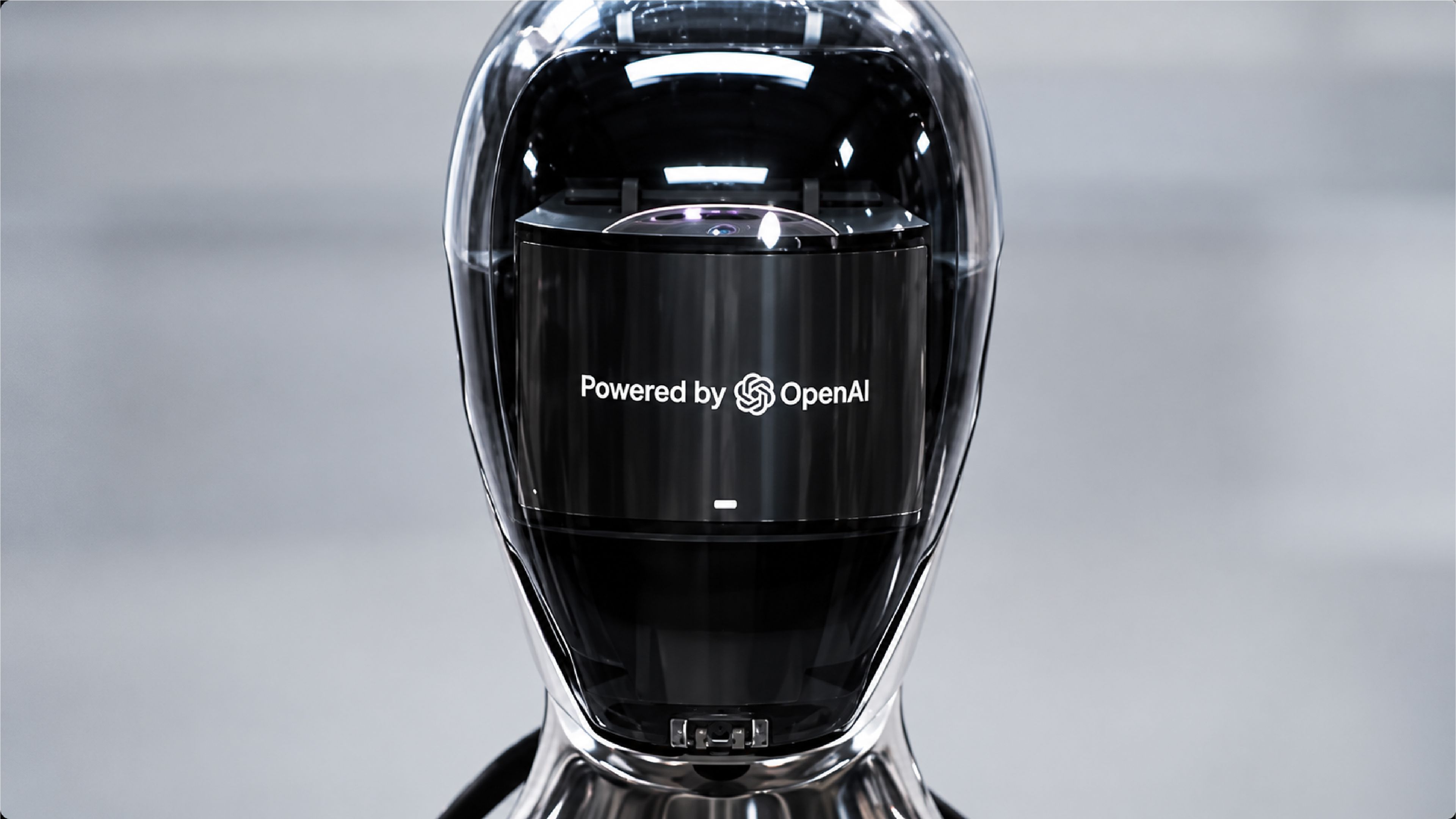 A futuristic humanoid robot's head with a black faceplate displaying the words "Powered by OpenAI" and the OpenAI logo.