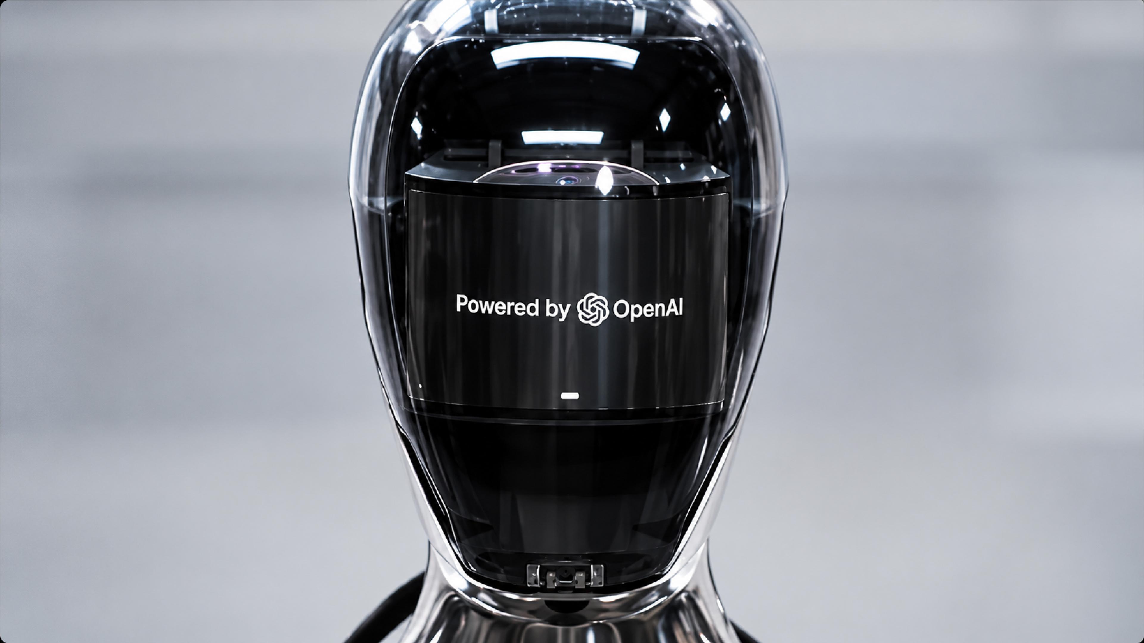A futuristic humanoid robot's head with a black faceplate displaying the words "Powered by OpenAI" and the OpenAI logo.