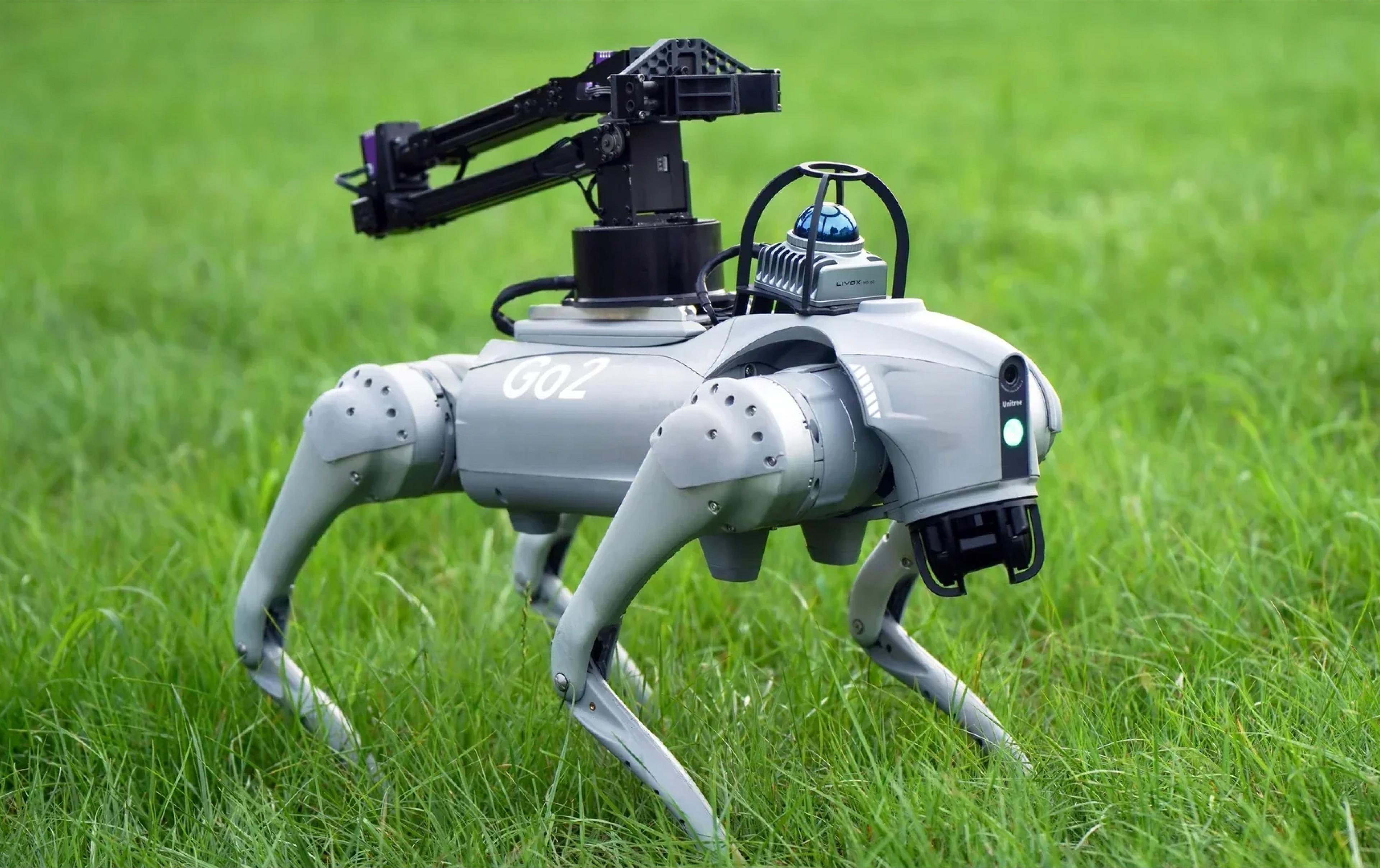 A robot dog sits in the grass, equipped with a camera, showcasing its advanced technology in a natural setting.