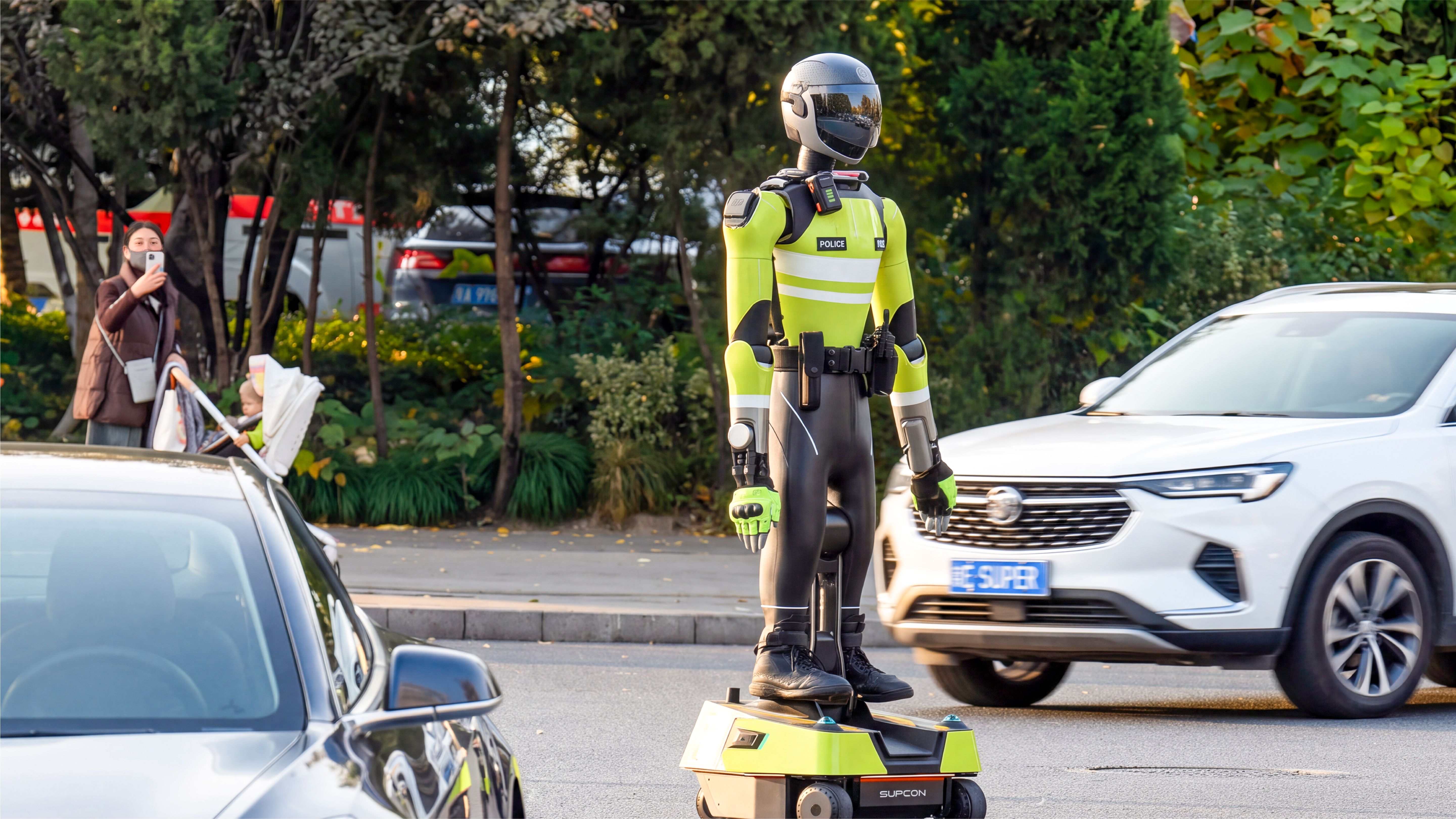 A humanoid robot dressed in a police uniform and helmet stands balanced on a wheeled mobility base