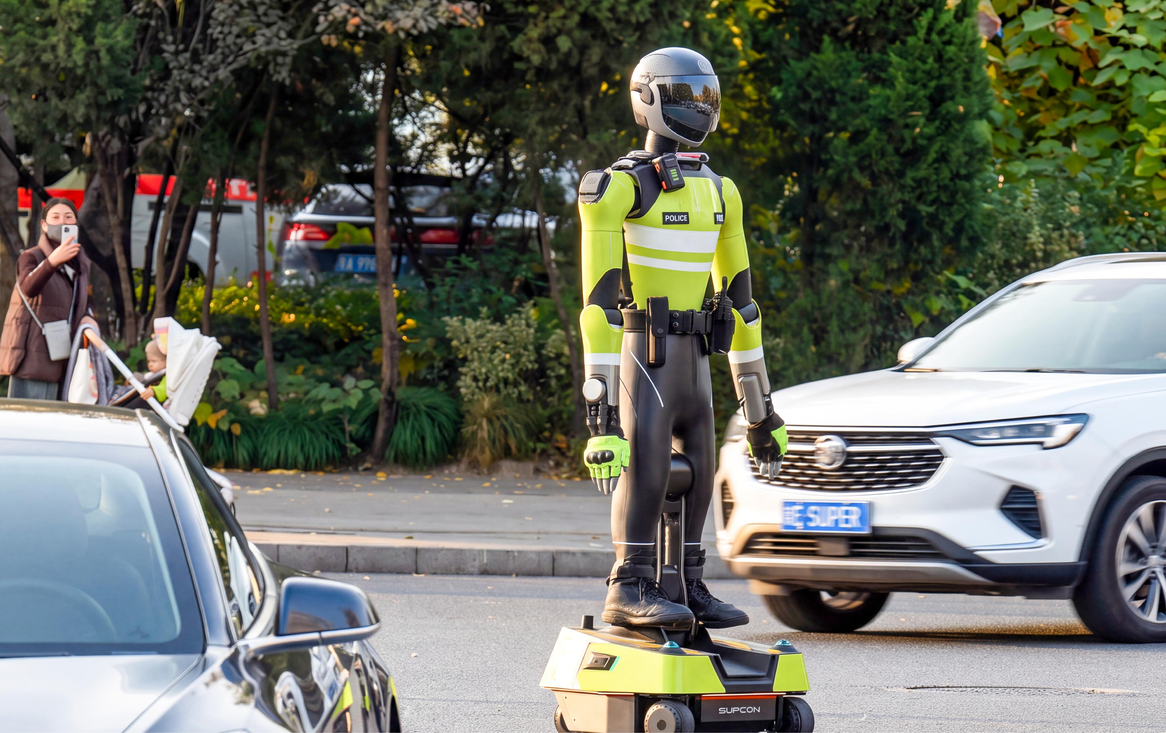 A humanoid robot dressed in a police uniform and helmet stands balanced on a wheeled mobility base