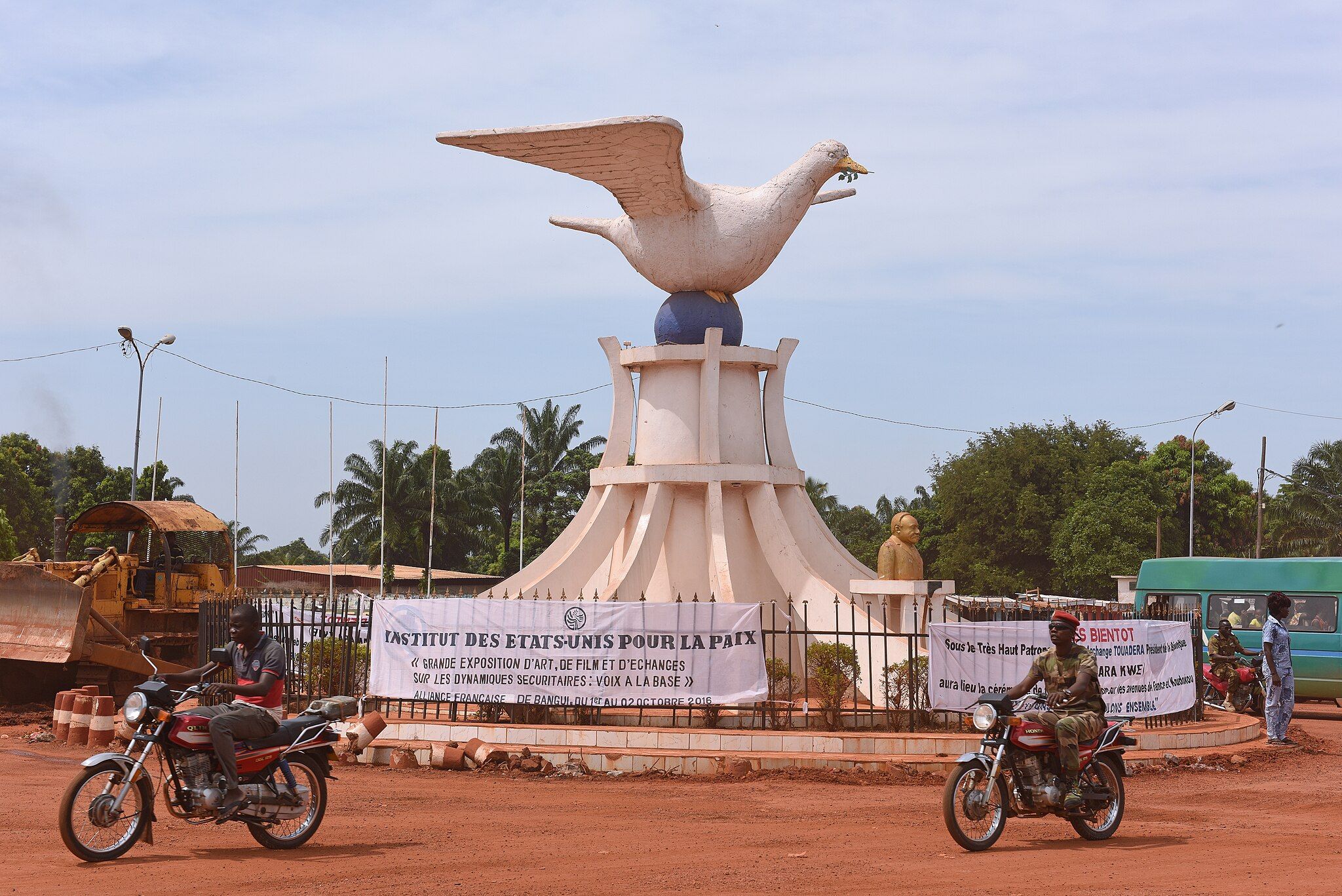 The Peace Dove of Bangui, a statue with men on motobikes in front.