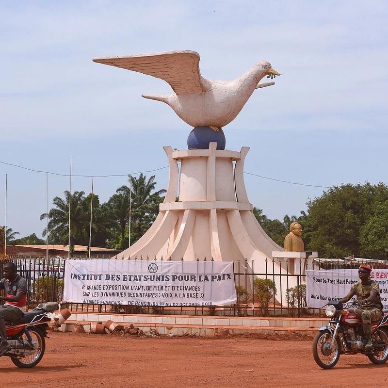 The Peace Dove of Bangui, a statue with men on motobikes in front.