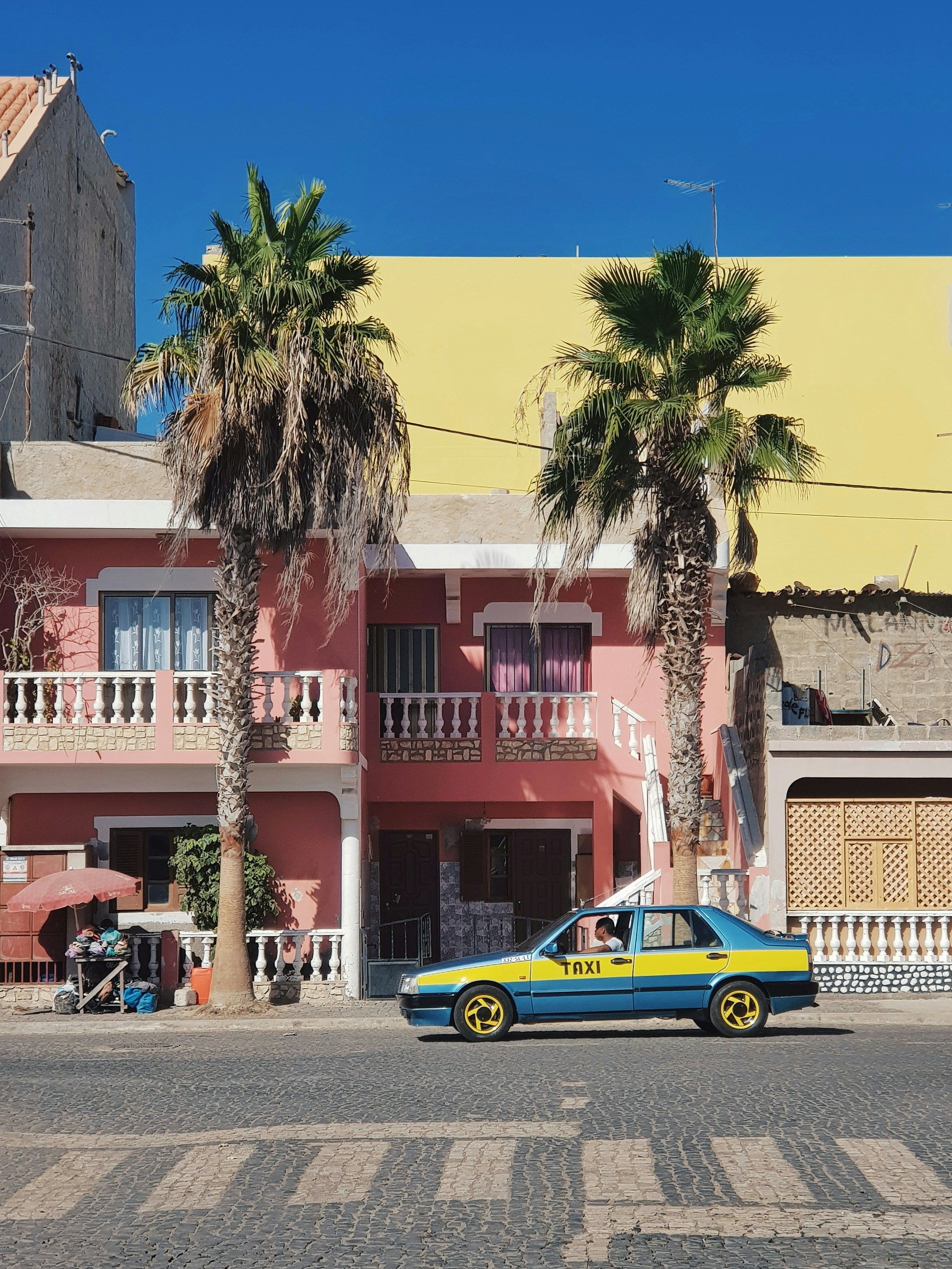 a taxi in front of bright buildings