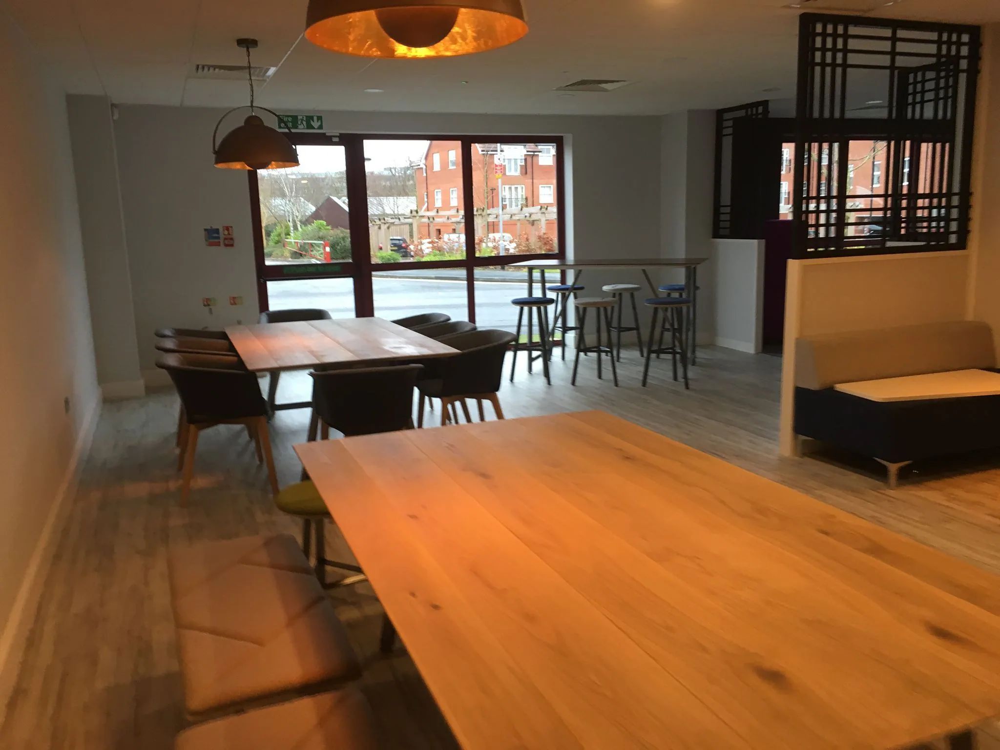 Refurbished workplace breakout area with timber tables and pendant lighting