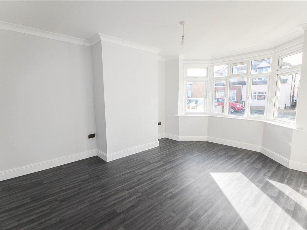 A refurbished living room with a bay window, fresh white walls and dark flooring