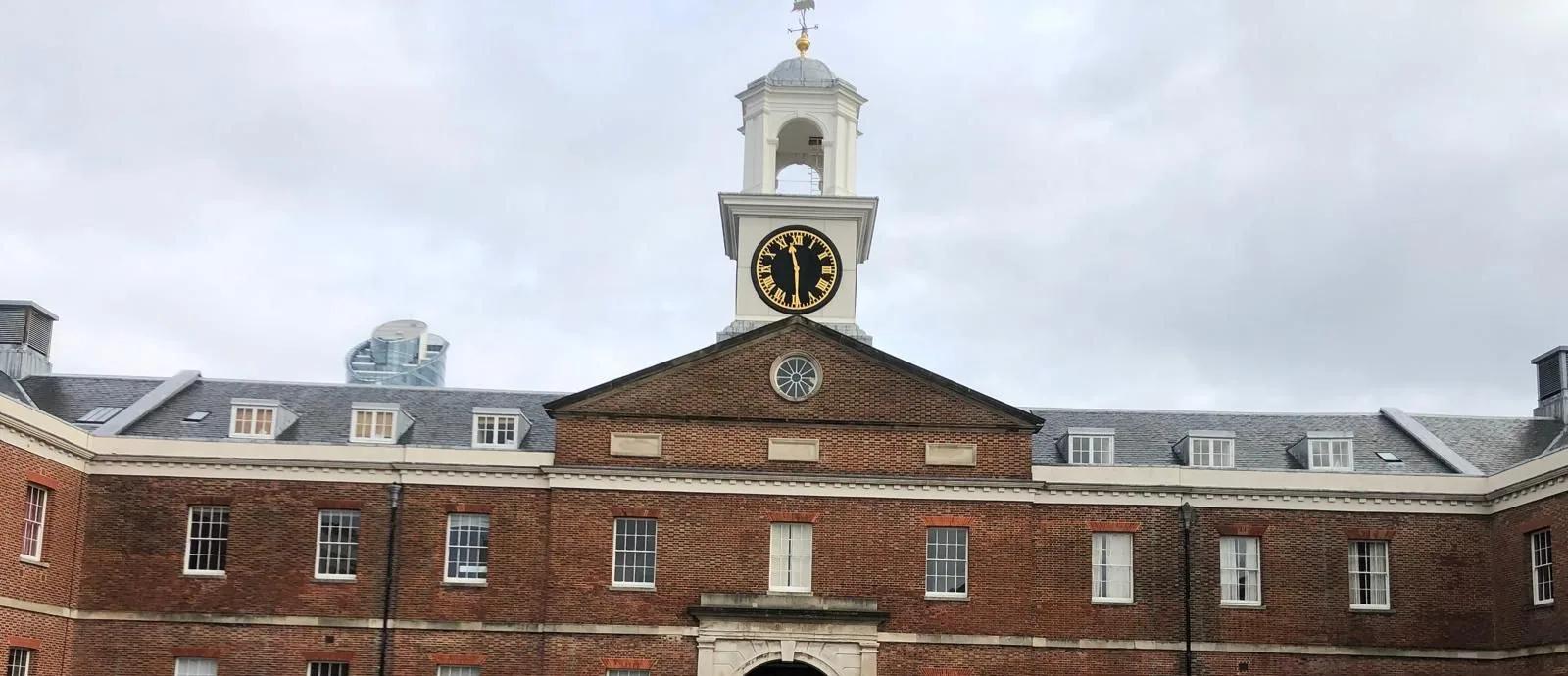Georgian red-brick quadrangle with a white clock tower and cupola above an arched central entrance