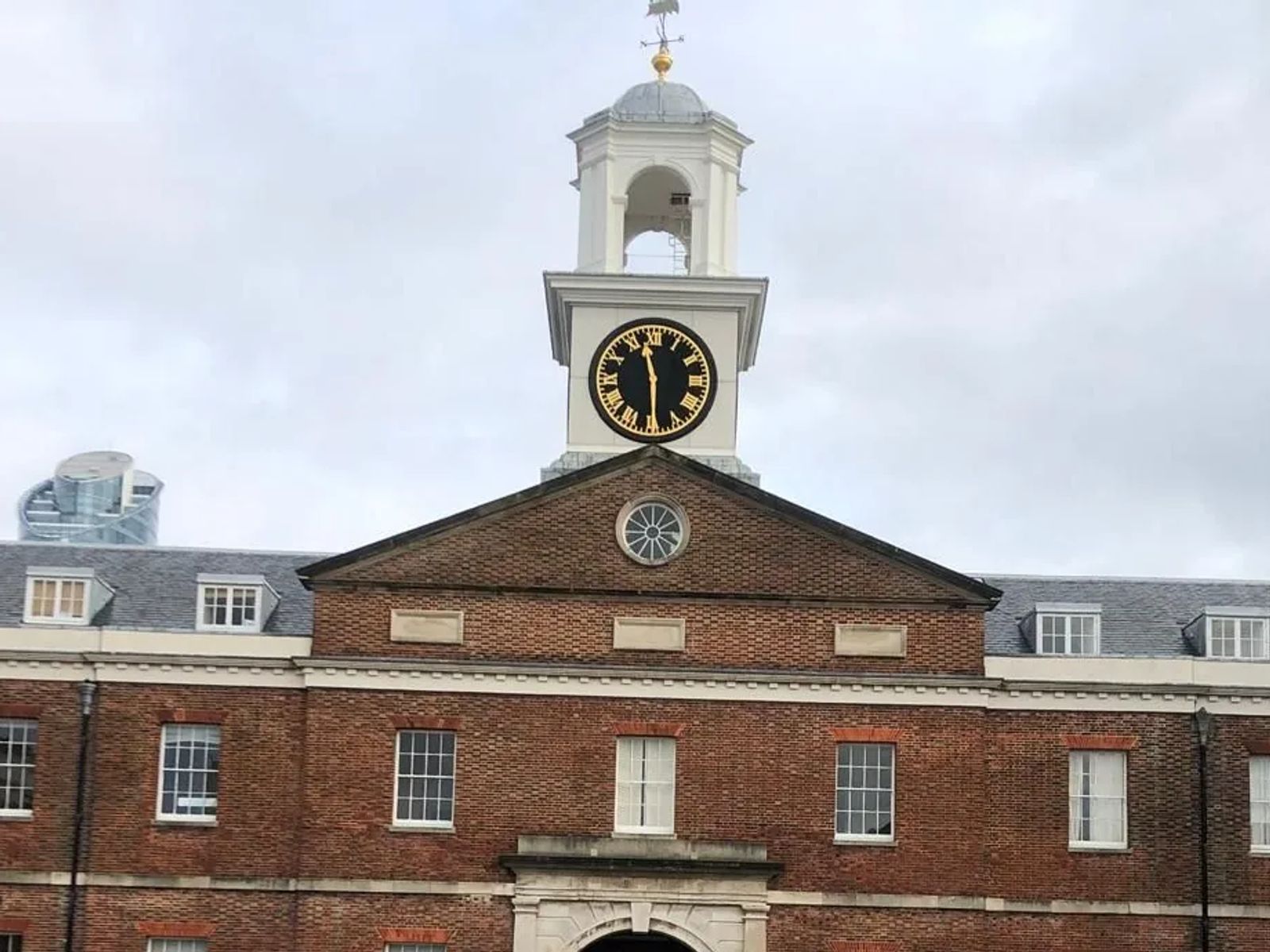 Georgian red-brick quadrangle with a white clock tower and cupola above an arched central entrance