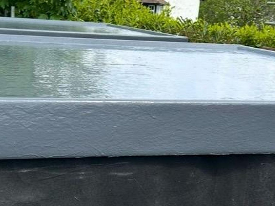 Low view across the liquid-coated flat roof and its raised perimeter