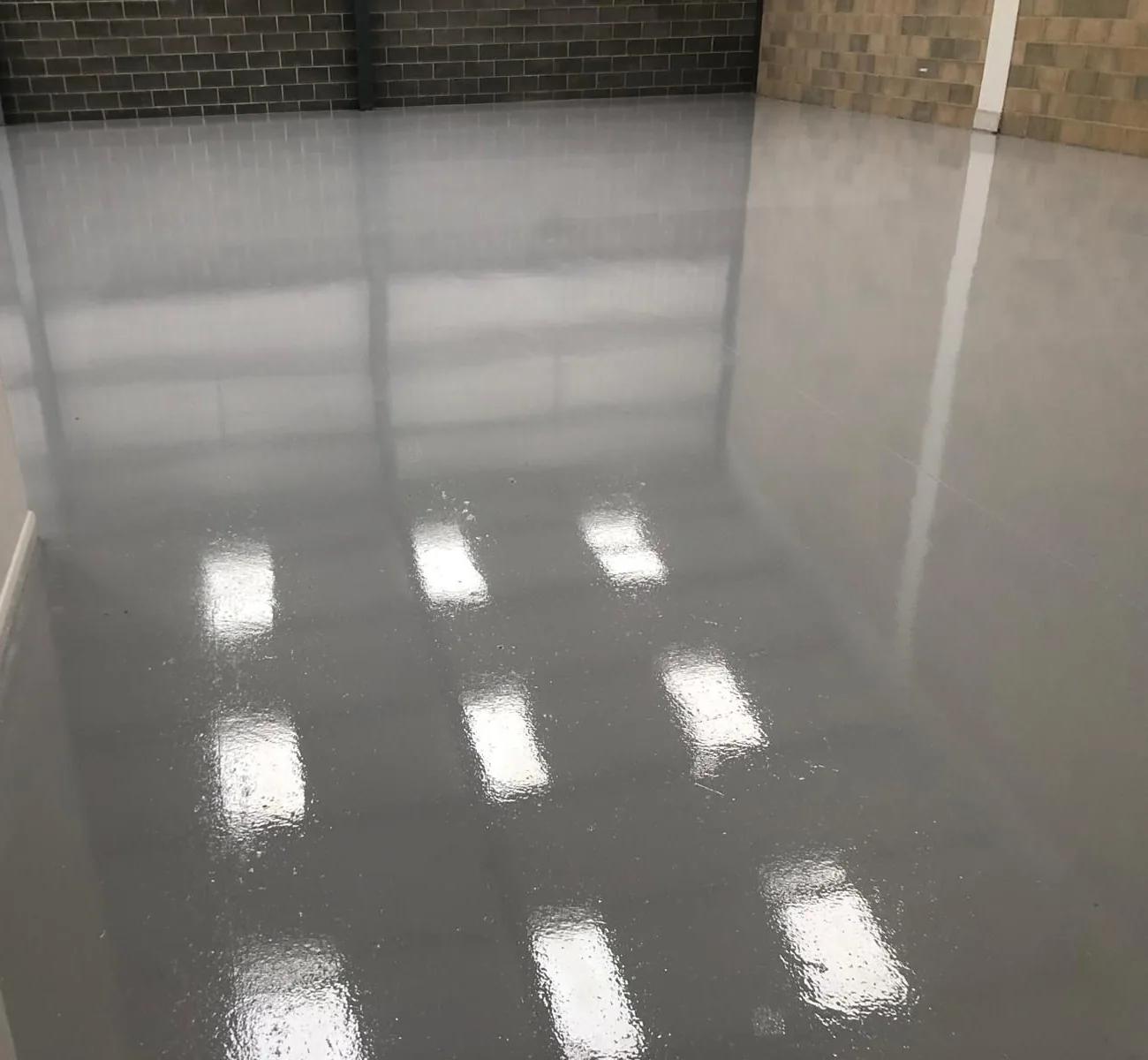 Poured grey resin floor across an industrial unit, with rooflights reflected in the finished surface