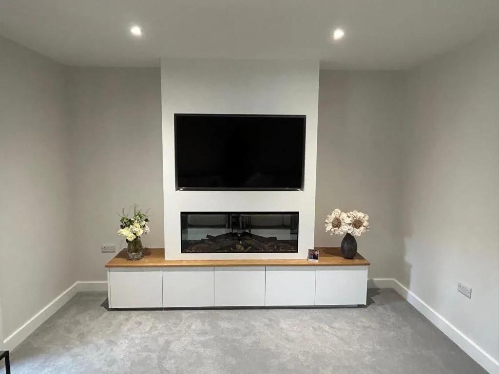 A long white media unit with an oak top and inset fire below a wall-mounted television