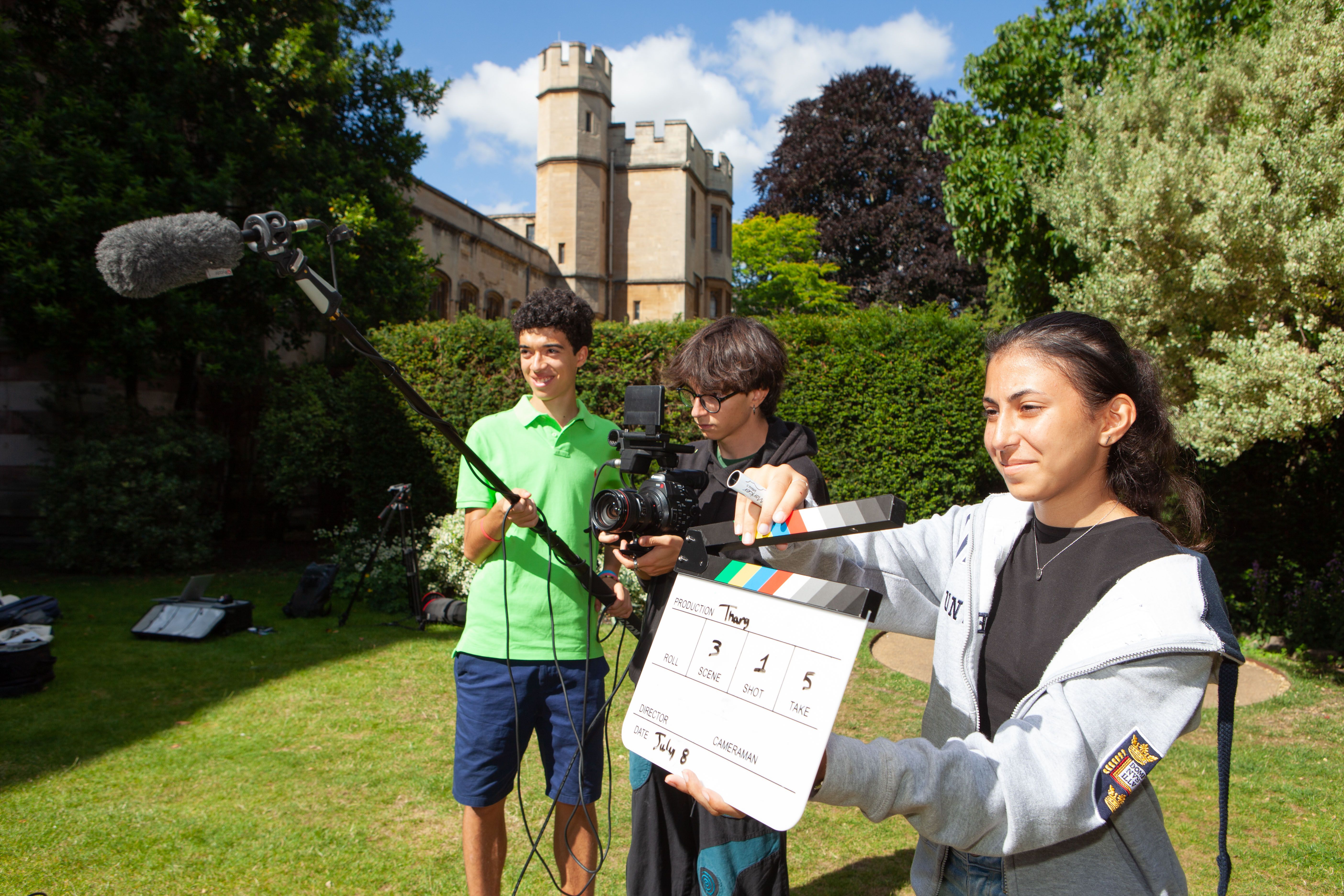 Students filming outside with a clapboard