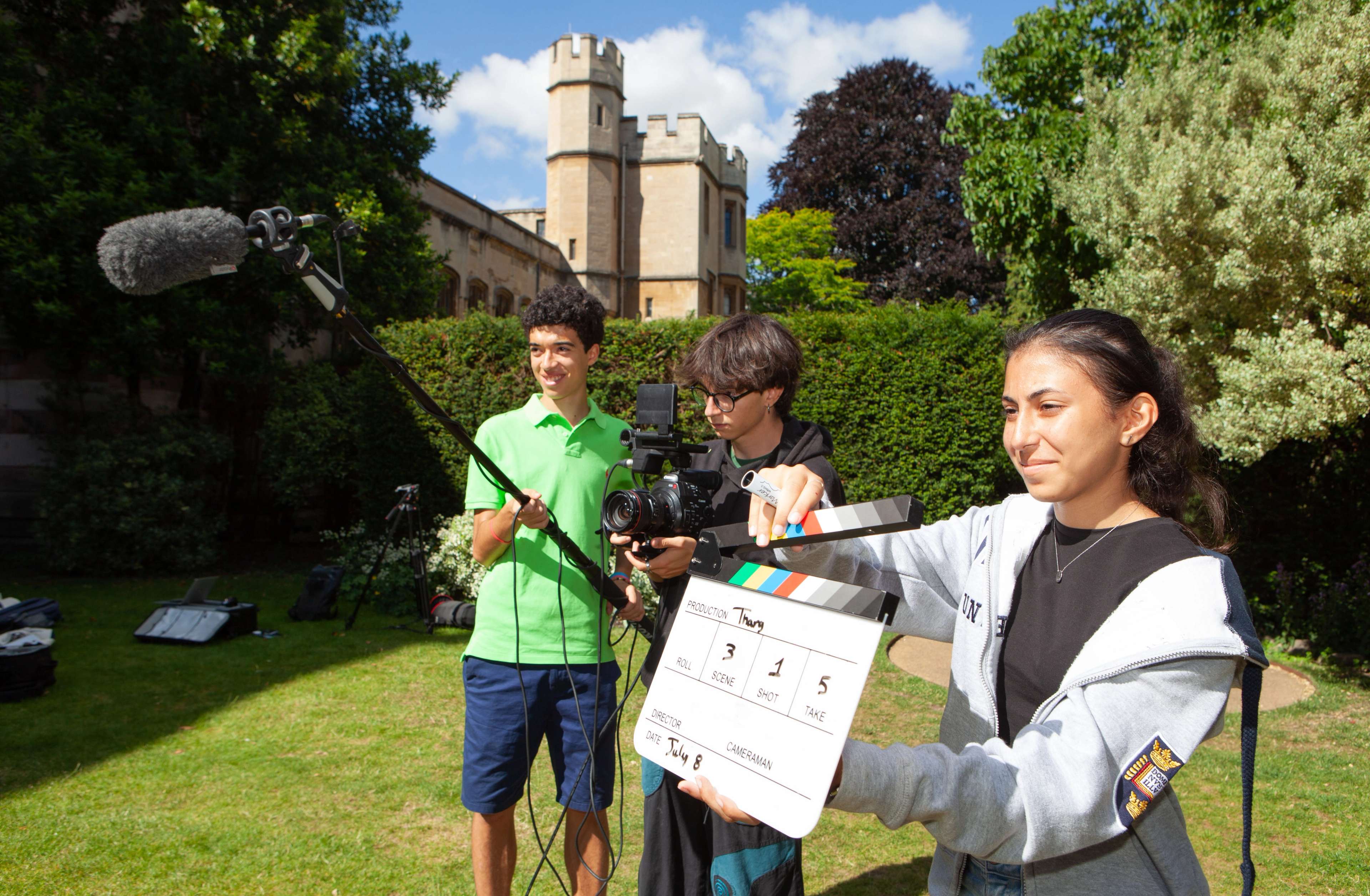 Students filming outside with a clapboard