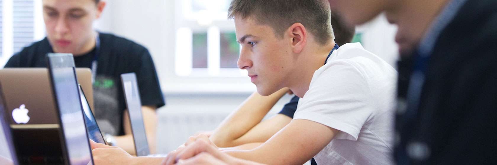 students sitting in a row working at a laptop concentrating