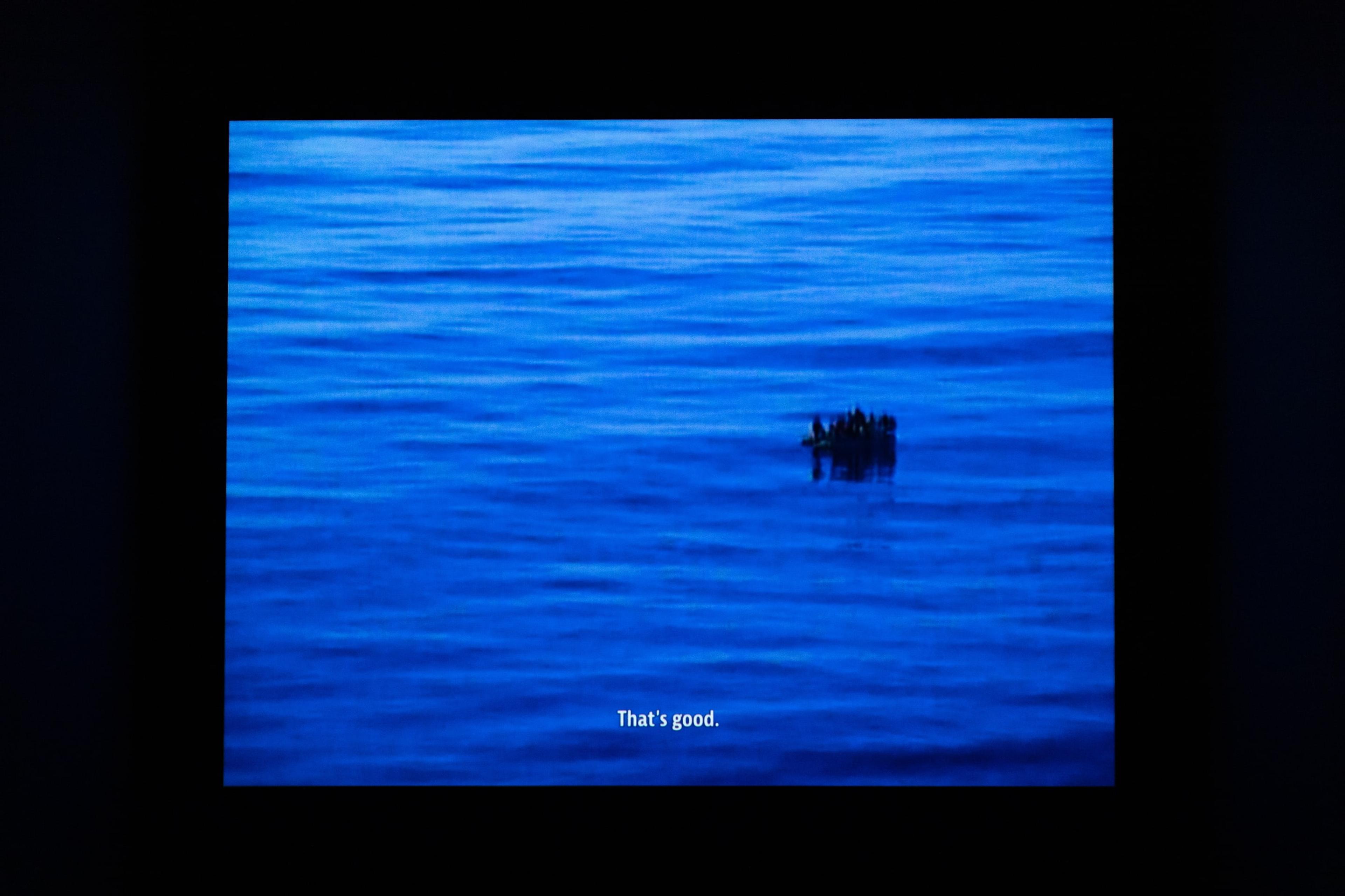 a projection of blue water and a floating black object, with a small subtitle reading "That's good"