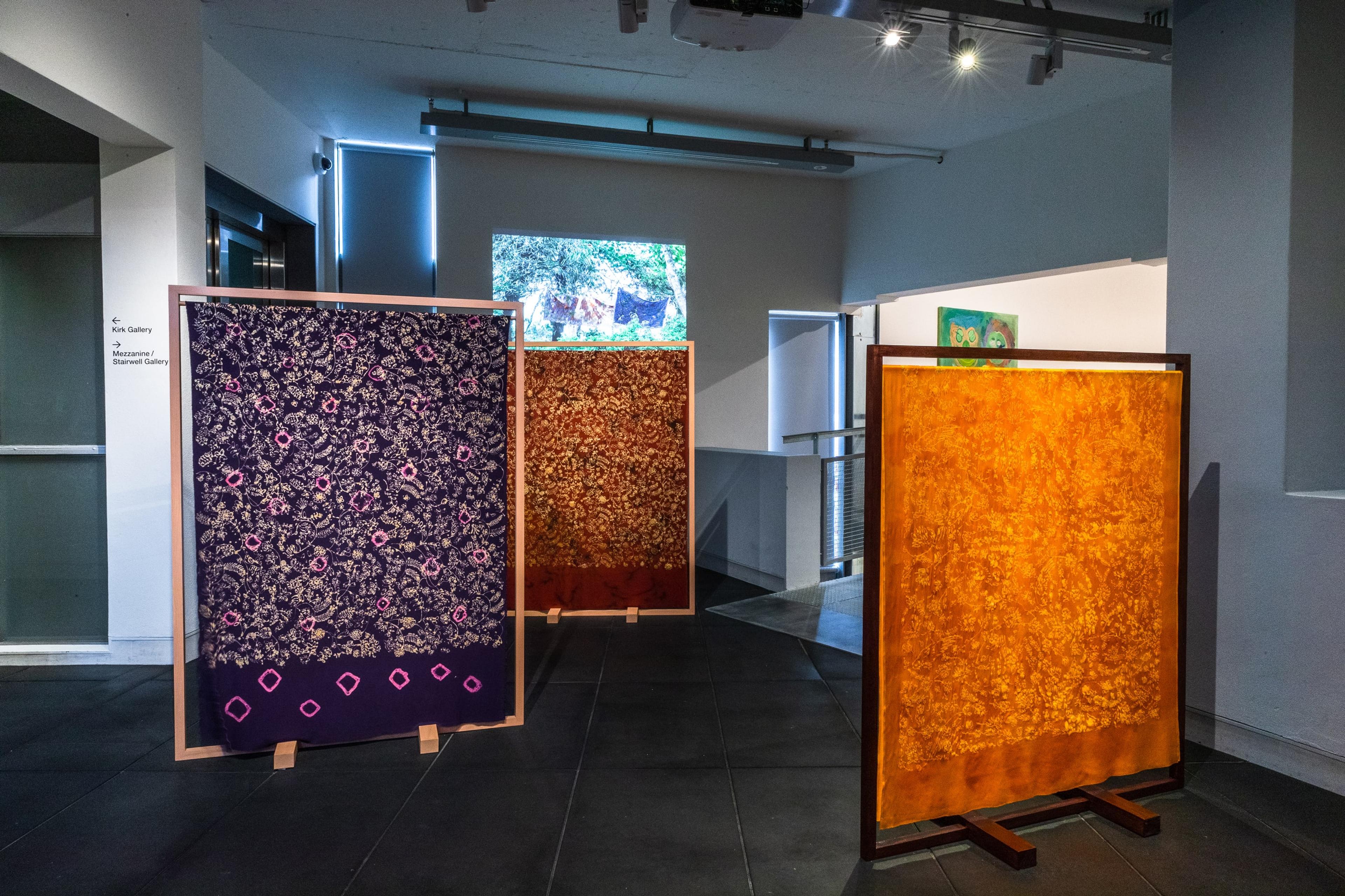 purple and orange fabric panels in a dim gallery space
