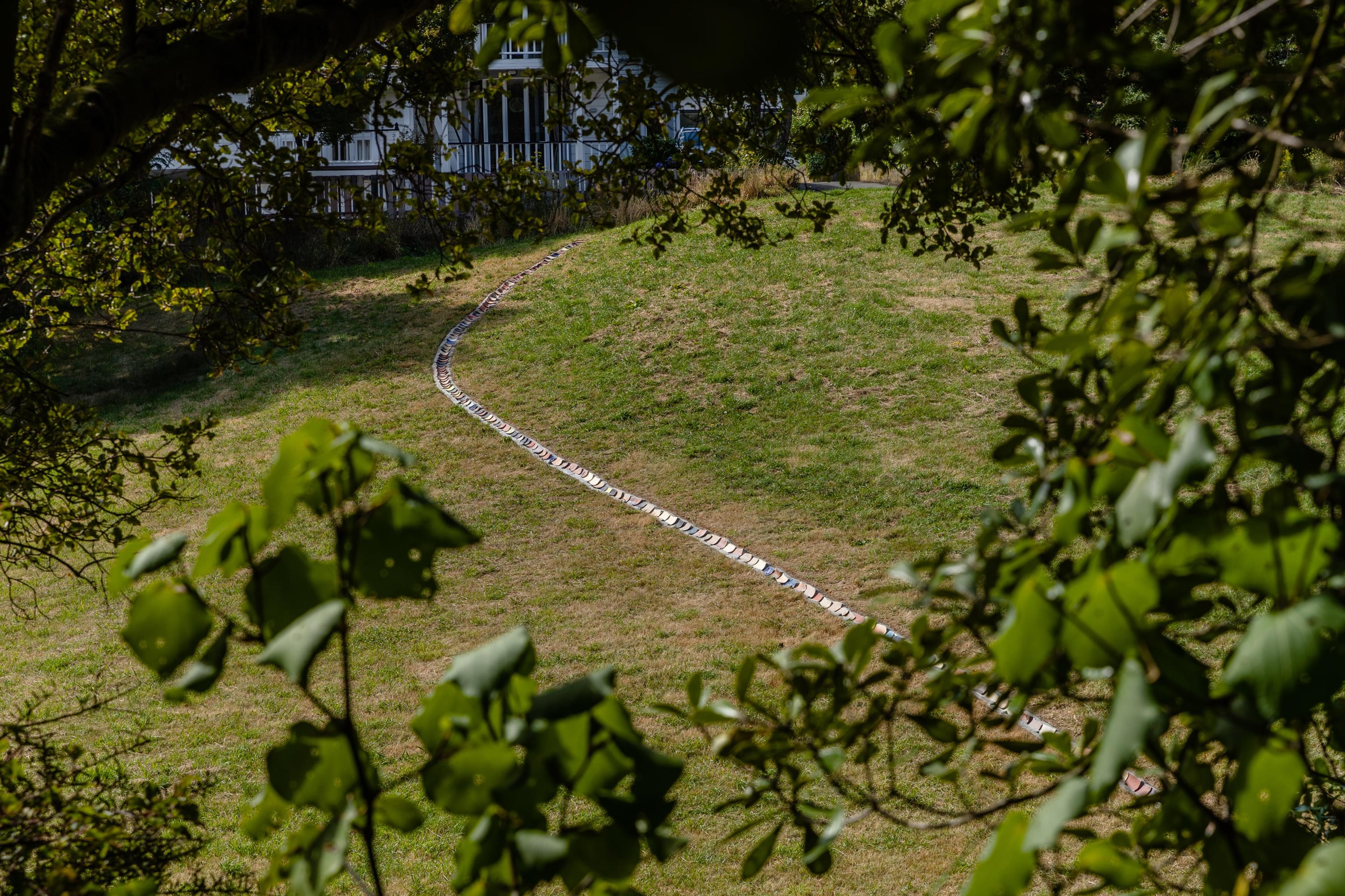 a long drain in a grass park, set with rounded terracotta tiles of different colours