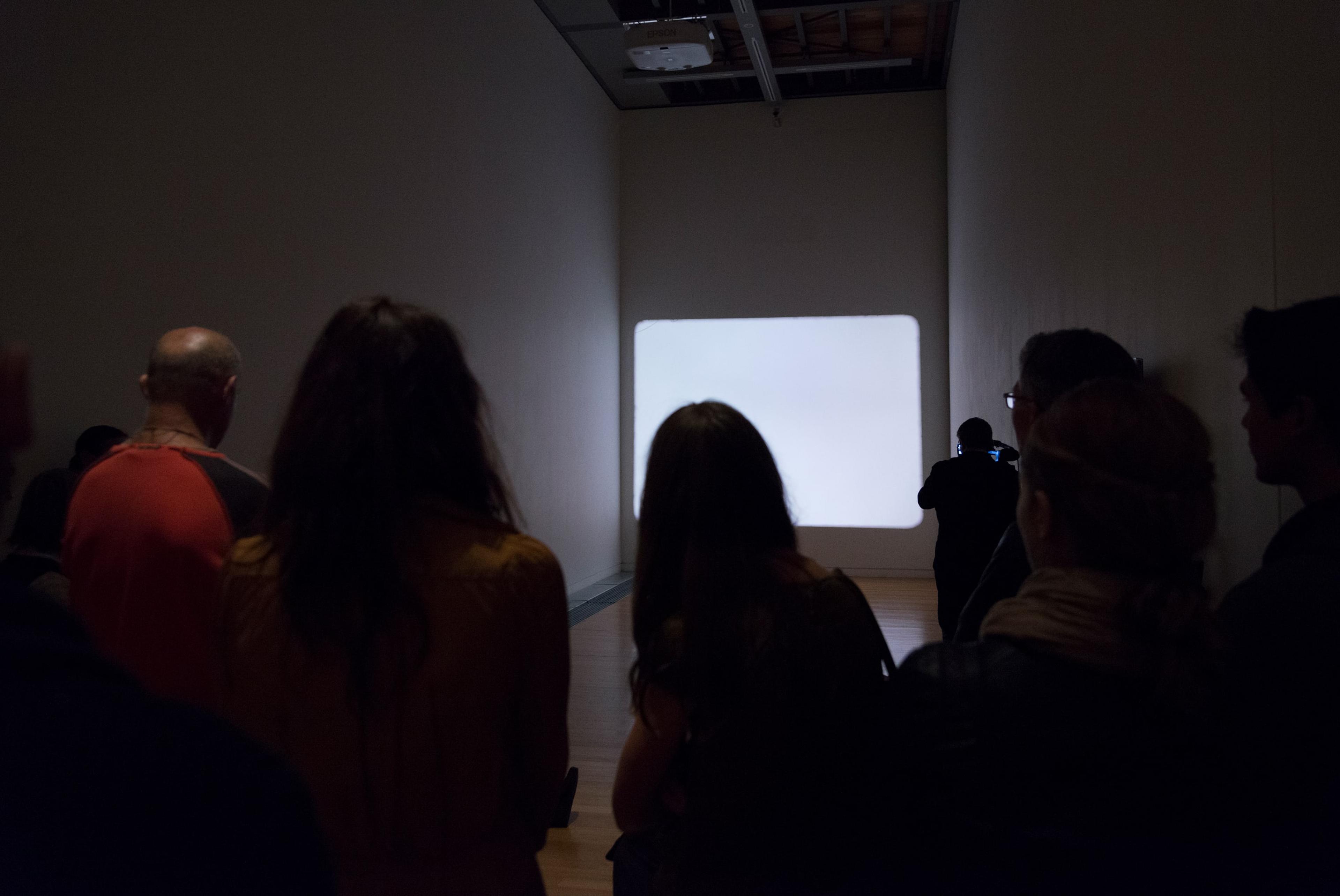 Hollis Frampton, A LECTURE, October 30, 1968, performed on February 11, 2014 by Martin Rumsby at the Adam Art Gallery. Script, 16mm projector, red filter, pipe cleaner. Courtesy of the Estate of Hollis Frampton. Photo: Shaun Waugh.