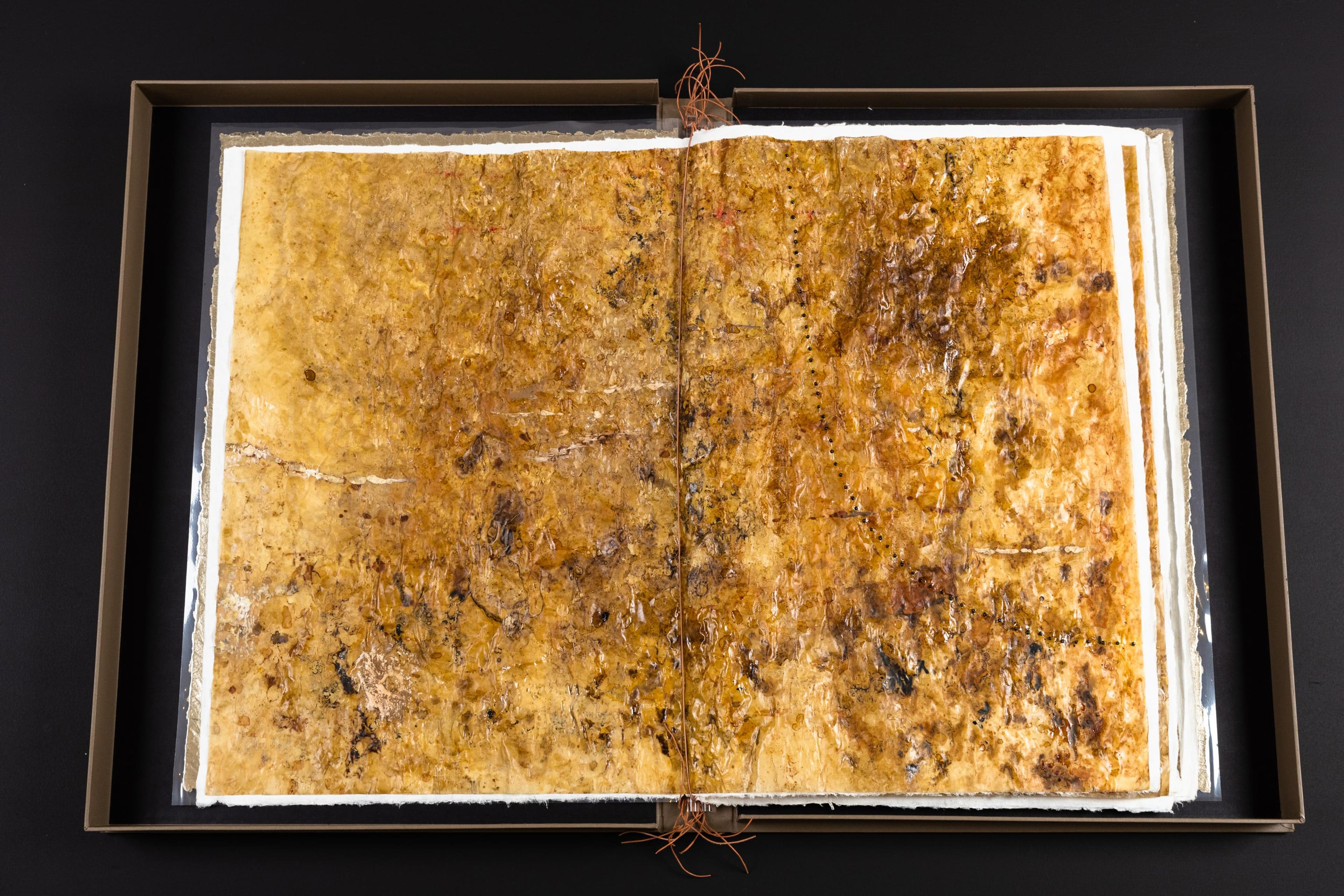 A flat brown and white book-like artwork on a low black bench table.