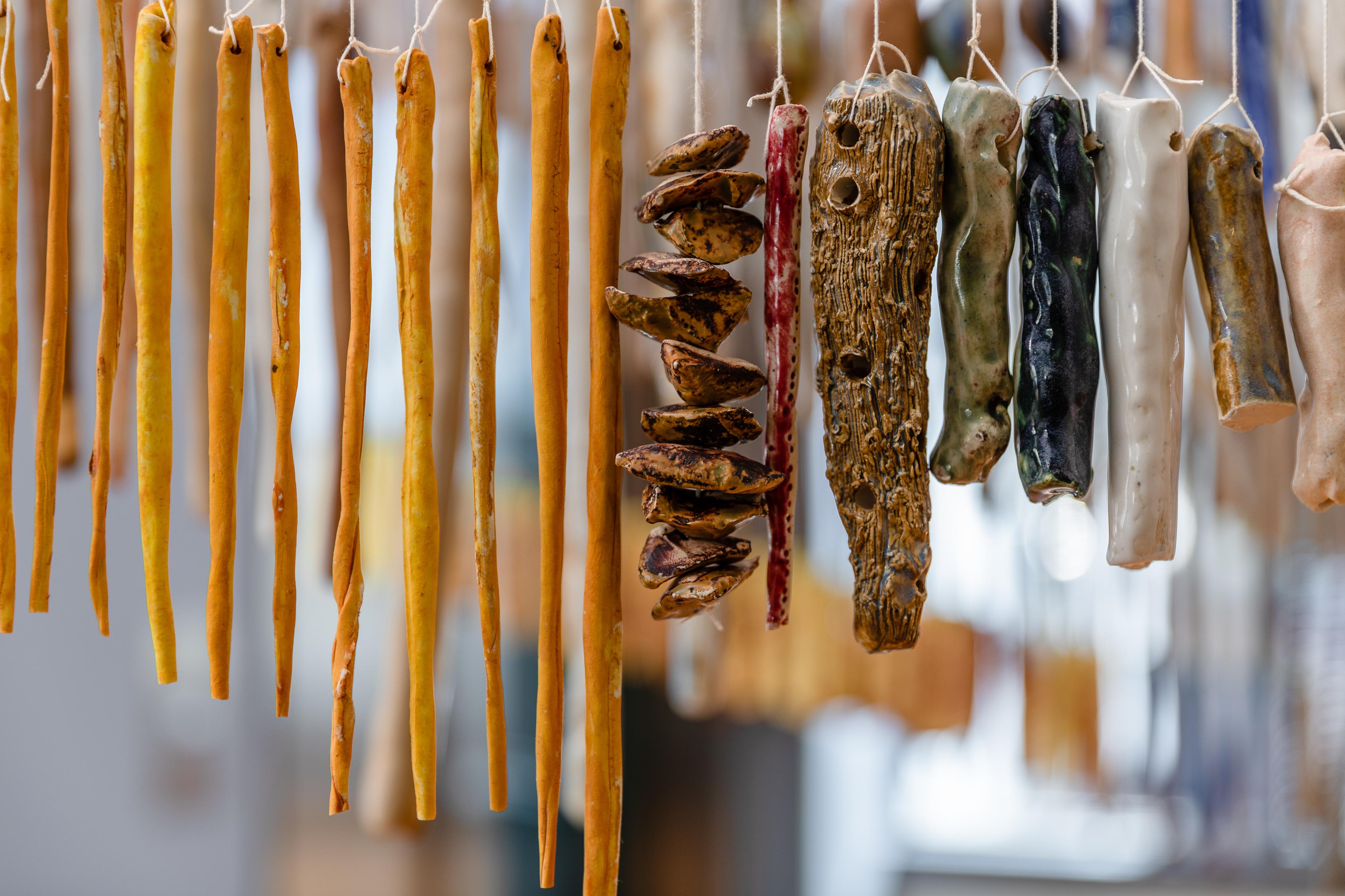 Ceramic of various colour and dimension suspended by string in a line.