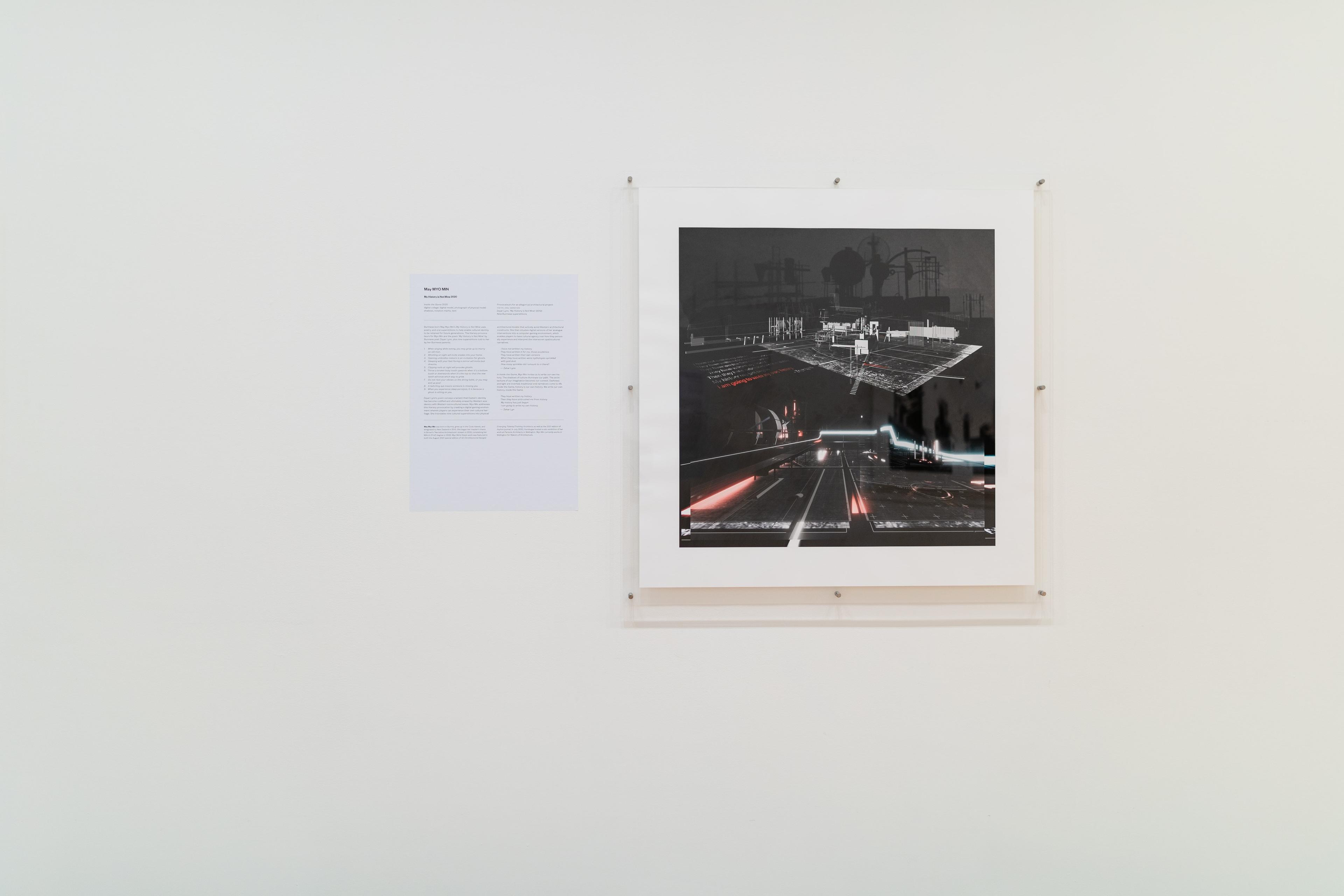 Straight on view of a gallery wall with text and a square architectural image in a perspex mount. Daniel K. Brown 