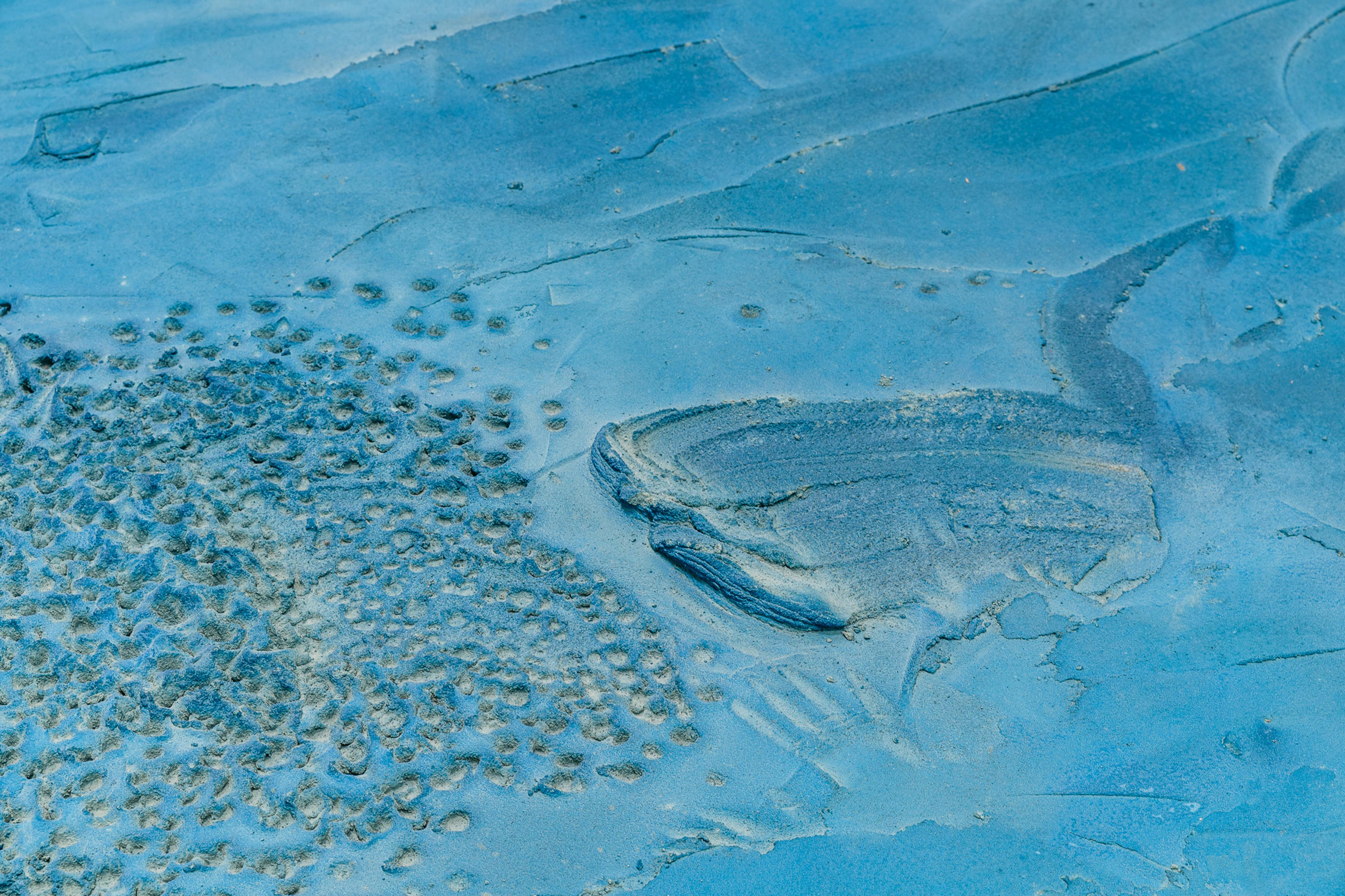 Detail of floor treated with screed, pigment, glass, silver. Blue colour