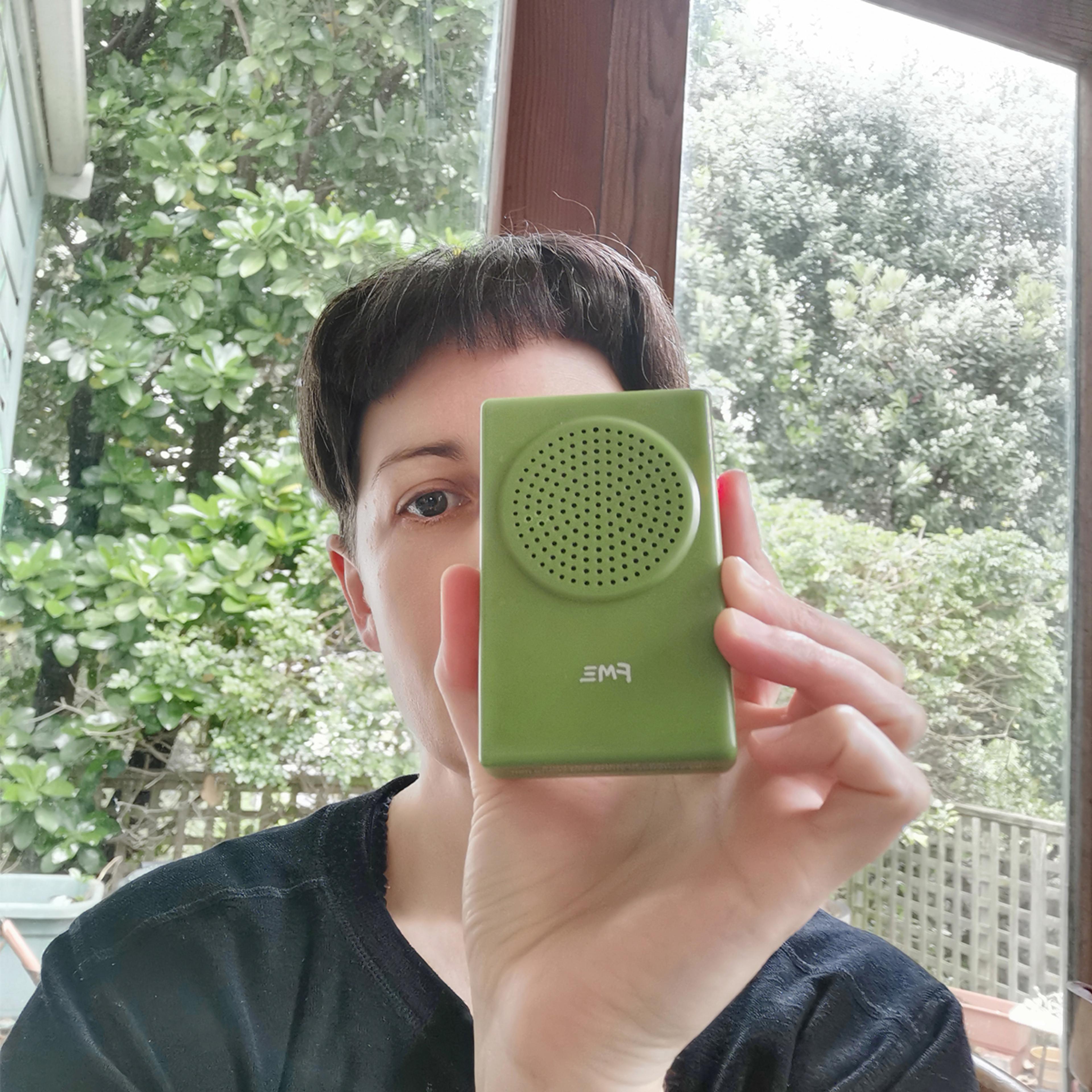 Rachel O'Neill holds a small green amp in front of her face