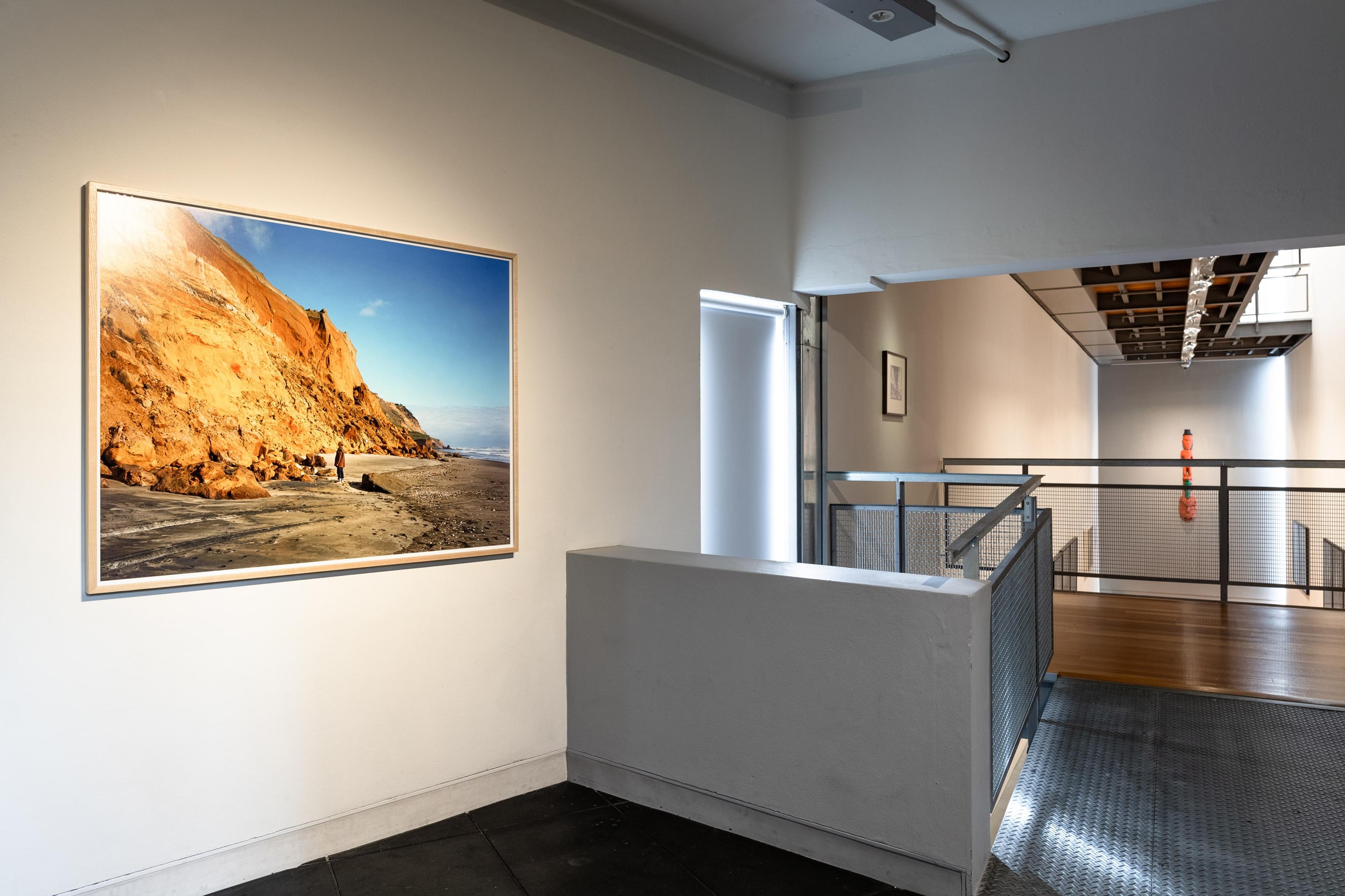 Chris Corson Scott, Mark Adams Before Cliffs and Rockfalls, Awhitu Peninsula, 2015, archival pigment print, courtesy of the artist and Trish Clark Gallery, Auckland. Installation view, Tēnei Ao Tūroa – This Enduring World, Te Pātaka Toi Adam Art Gallery, Victoria University Wellington. Photo: Ted Whitaker