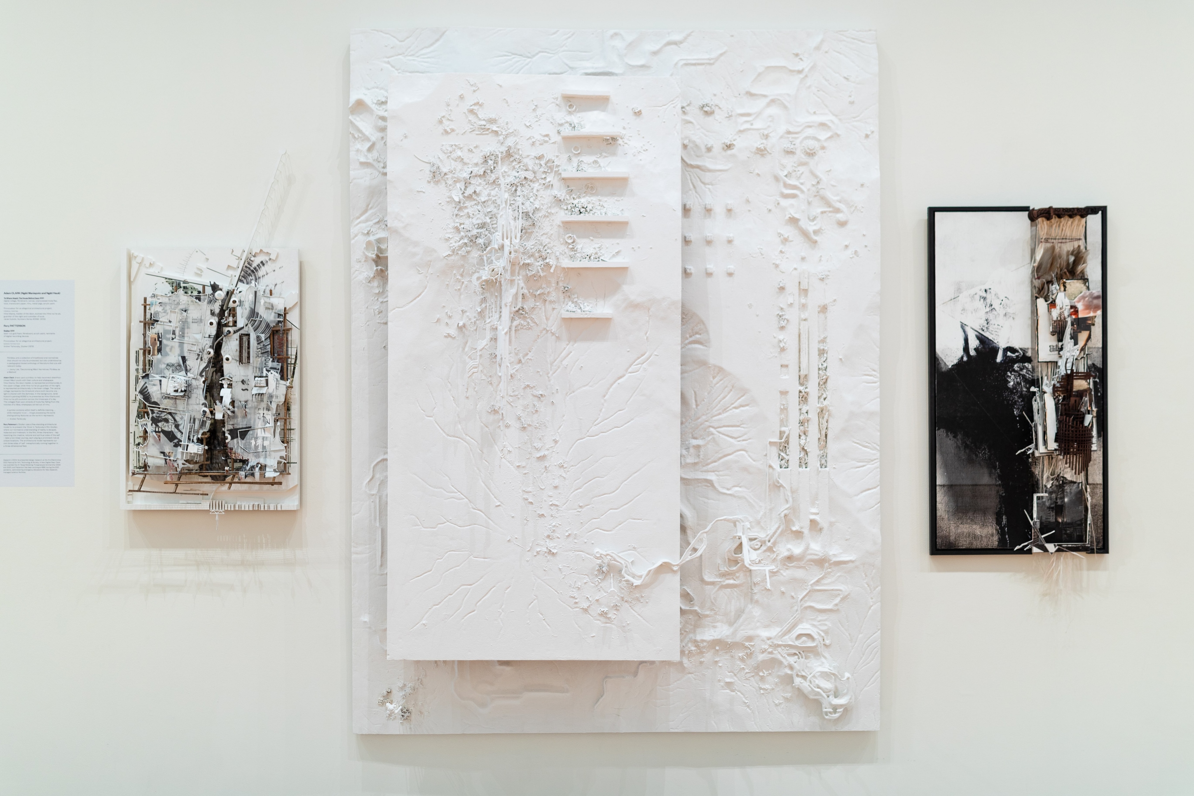 Straight on view of a gallery wall with a white rectangular relief sculpture, and two smaller ones on either side. Daniel K. Brown 