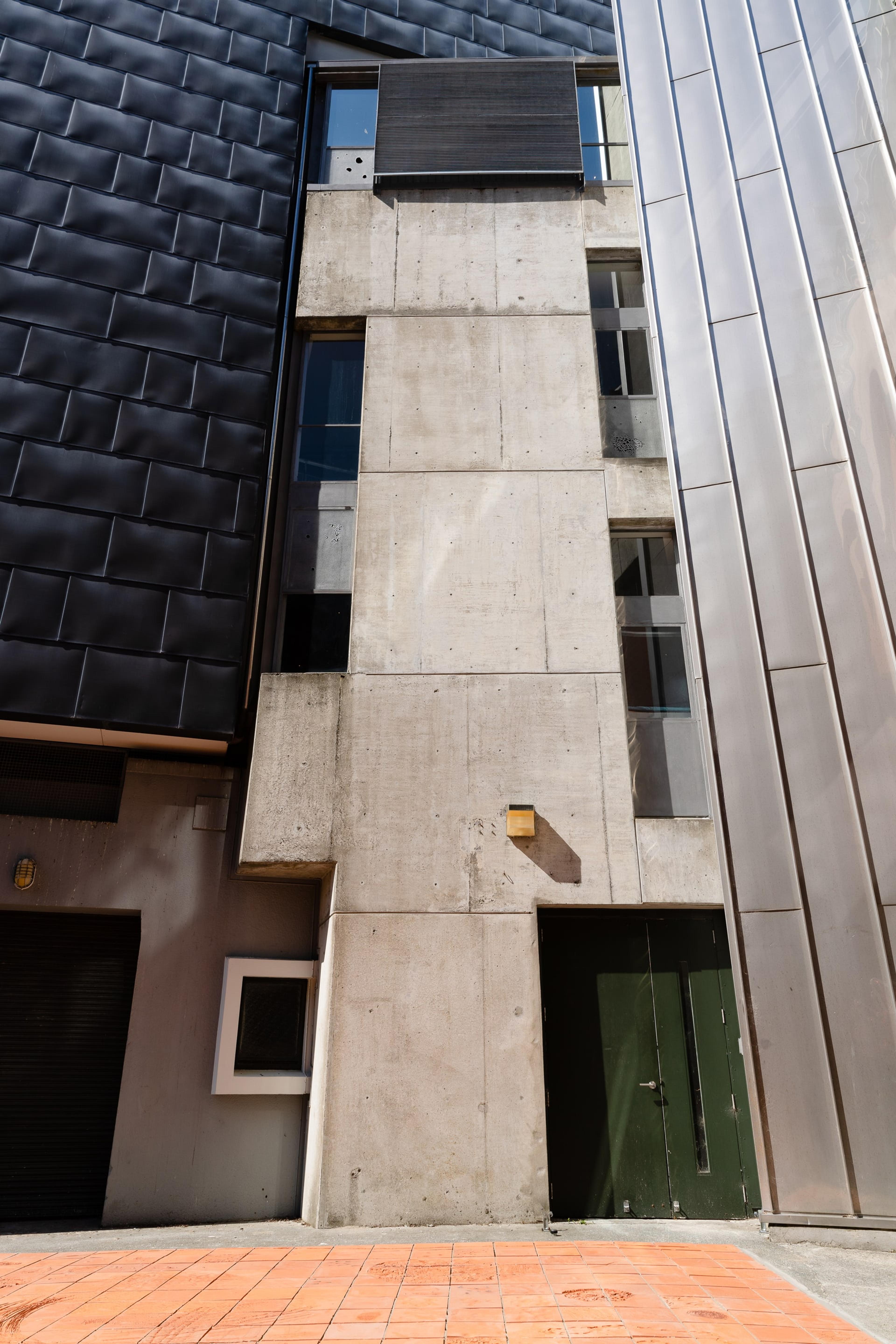 photograph of a flat area of terracotta tiles next to a tall grey concrete building