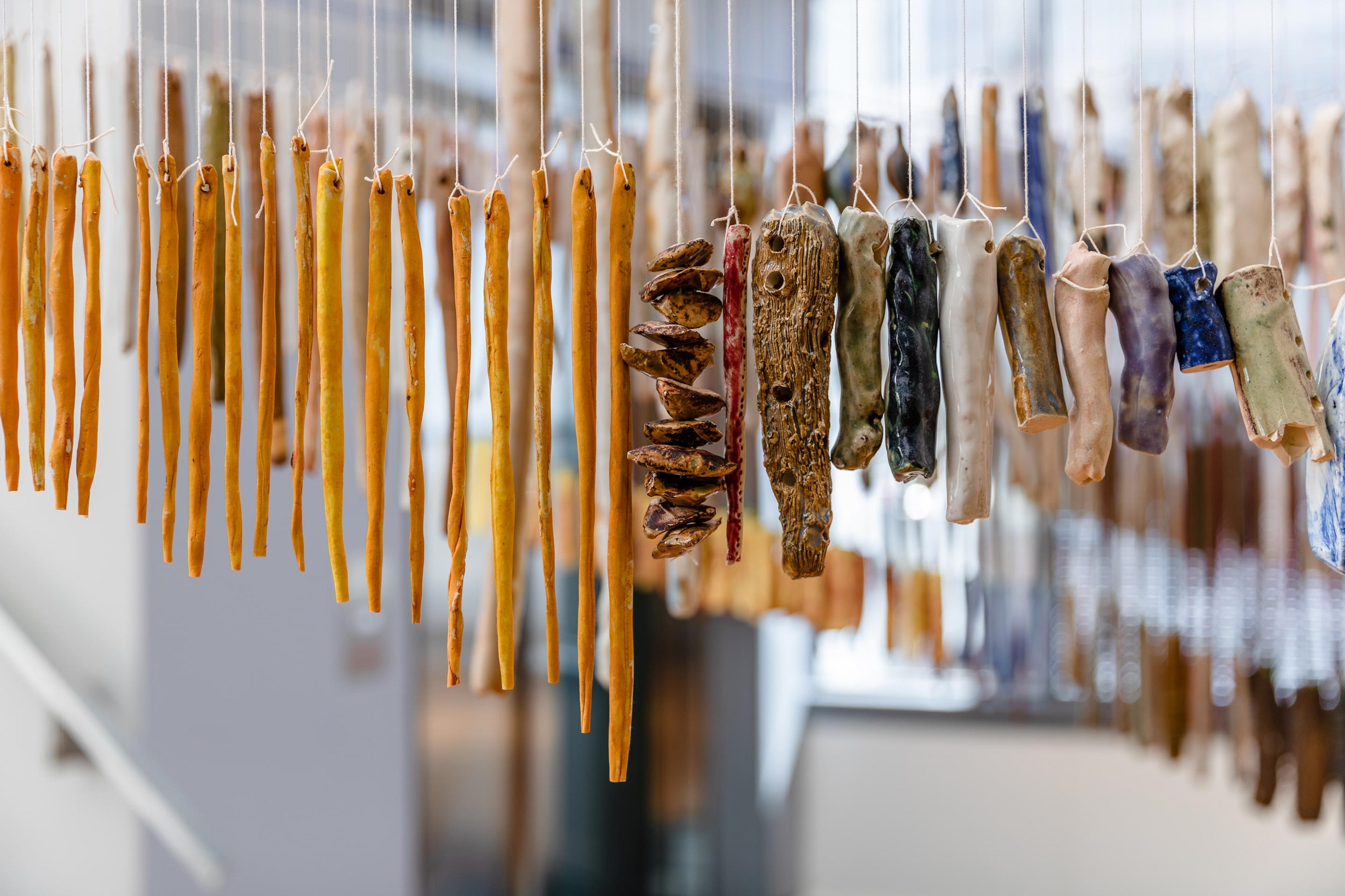 closeup photo of fine, long ceramic objects dangling from thin strings