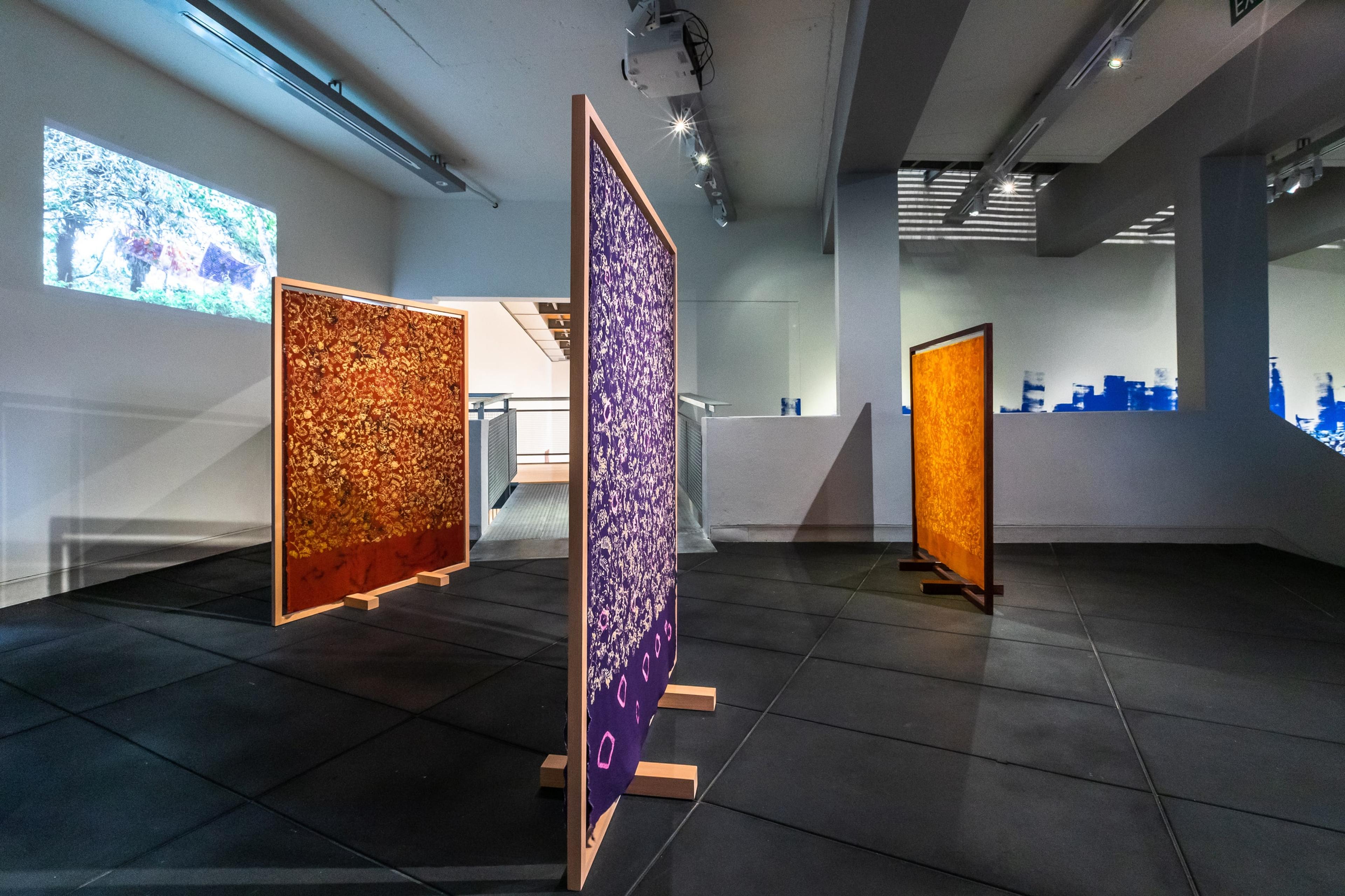 purple and orange fabric panels in a dim gallery space