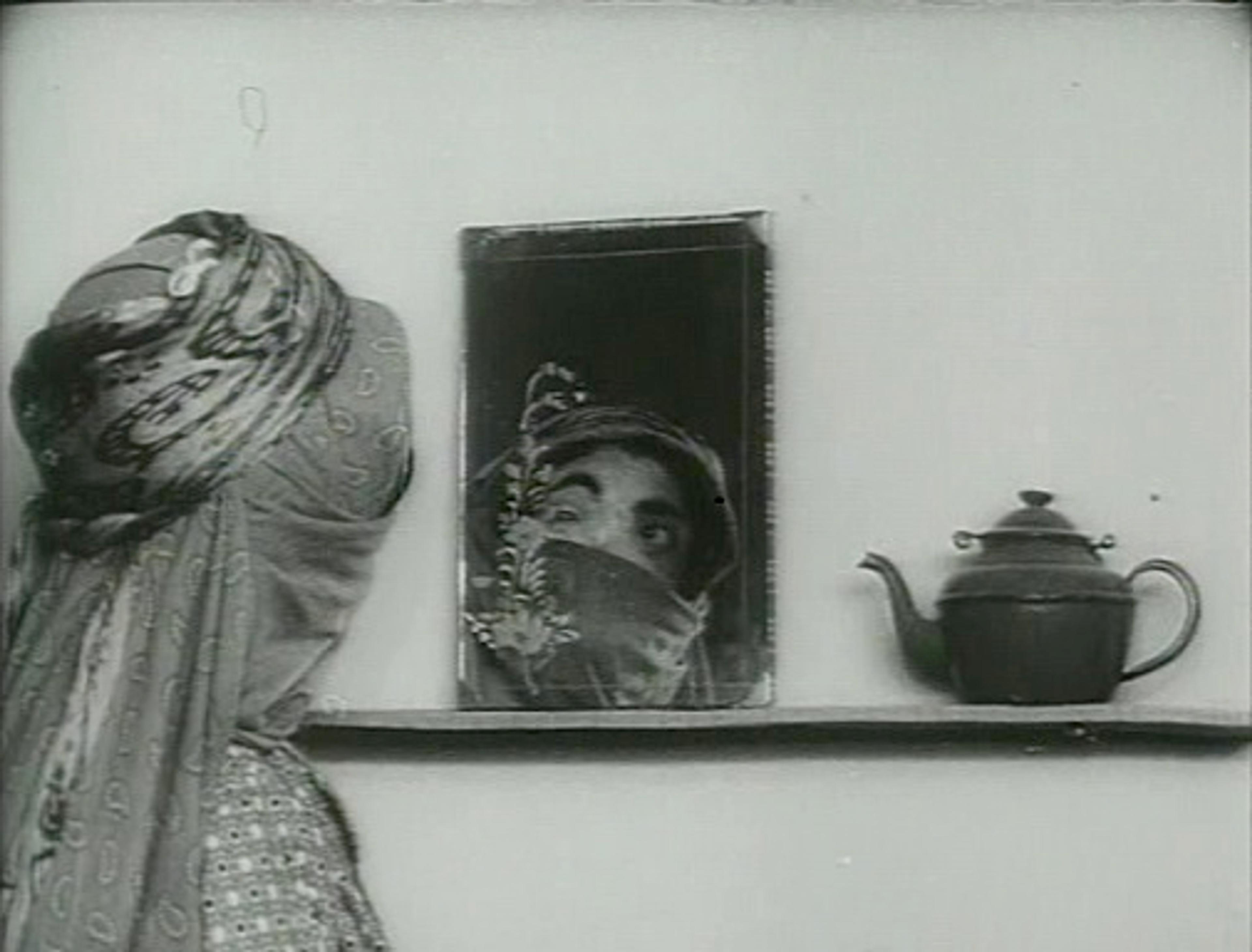 Women wearing head covering, looking into a mirror. 