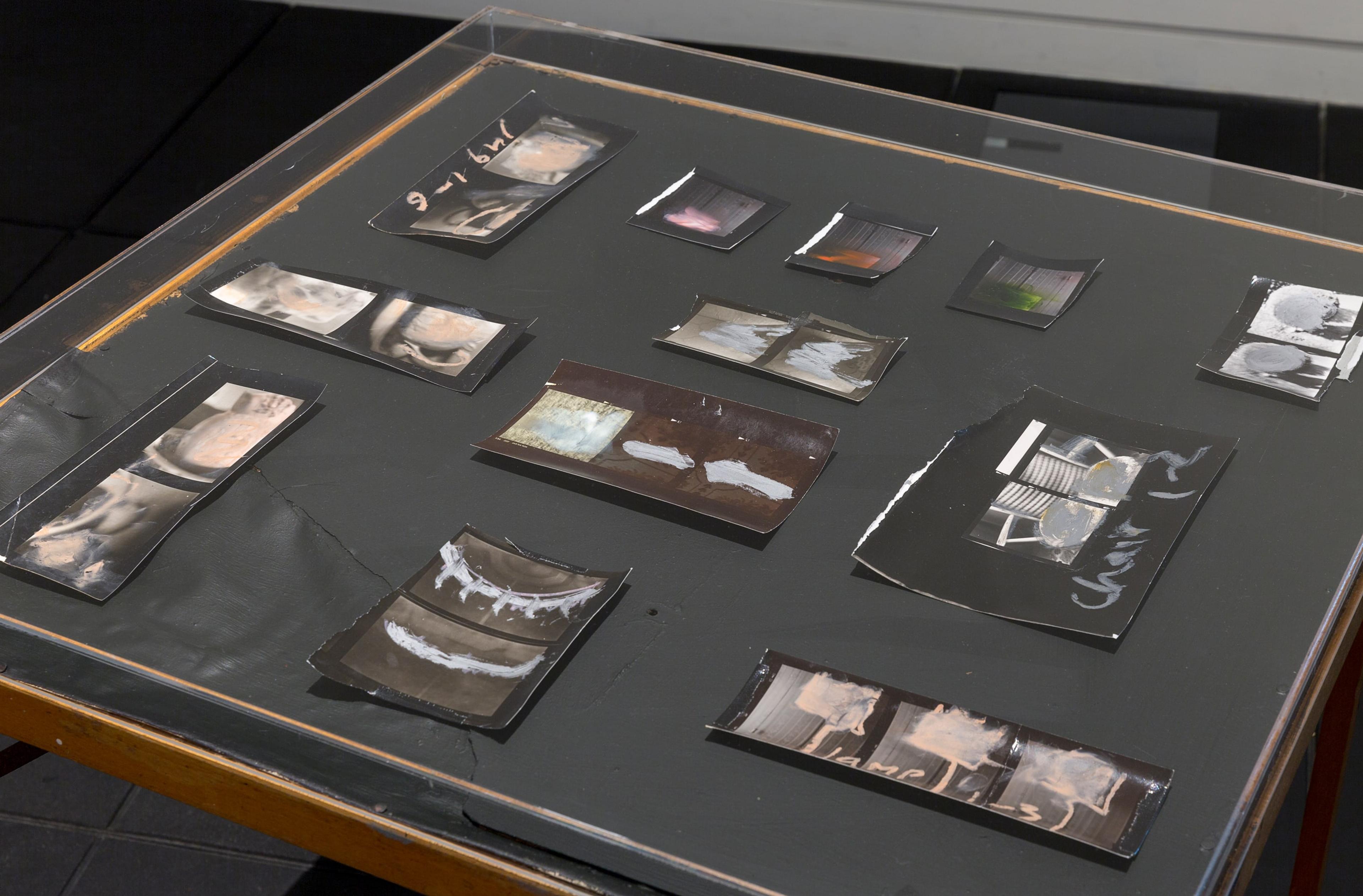 Minerva Betts, Untitled 1980–2015, silver bromide contact prints with oil pastel, table, Perspex. Courtesy of the Estate of L. Budd and Michael Lett, Auckland. In Fragments of a World, curated by Sandy Callister, Adam Art Gallery Te Pātaka Toi, Victoria University of Wellington (photo: Shaun Waugh)