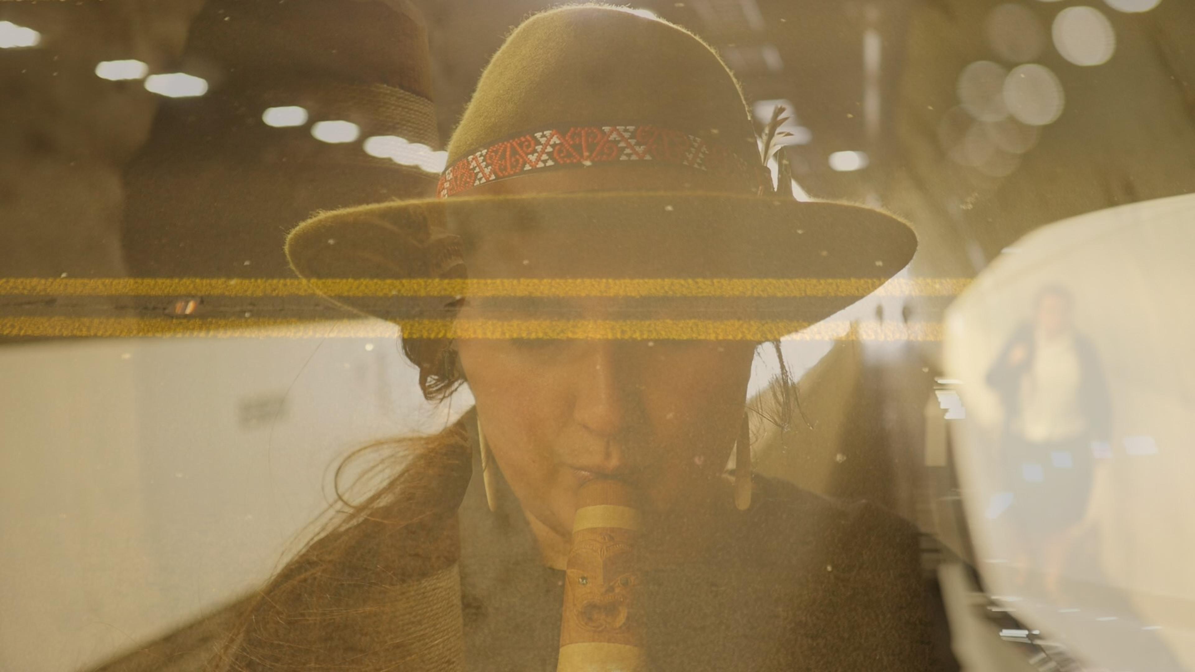 Ruby Solly playing a carved instrument, documented in a multiple exposure photograph.