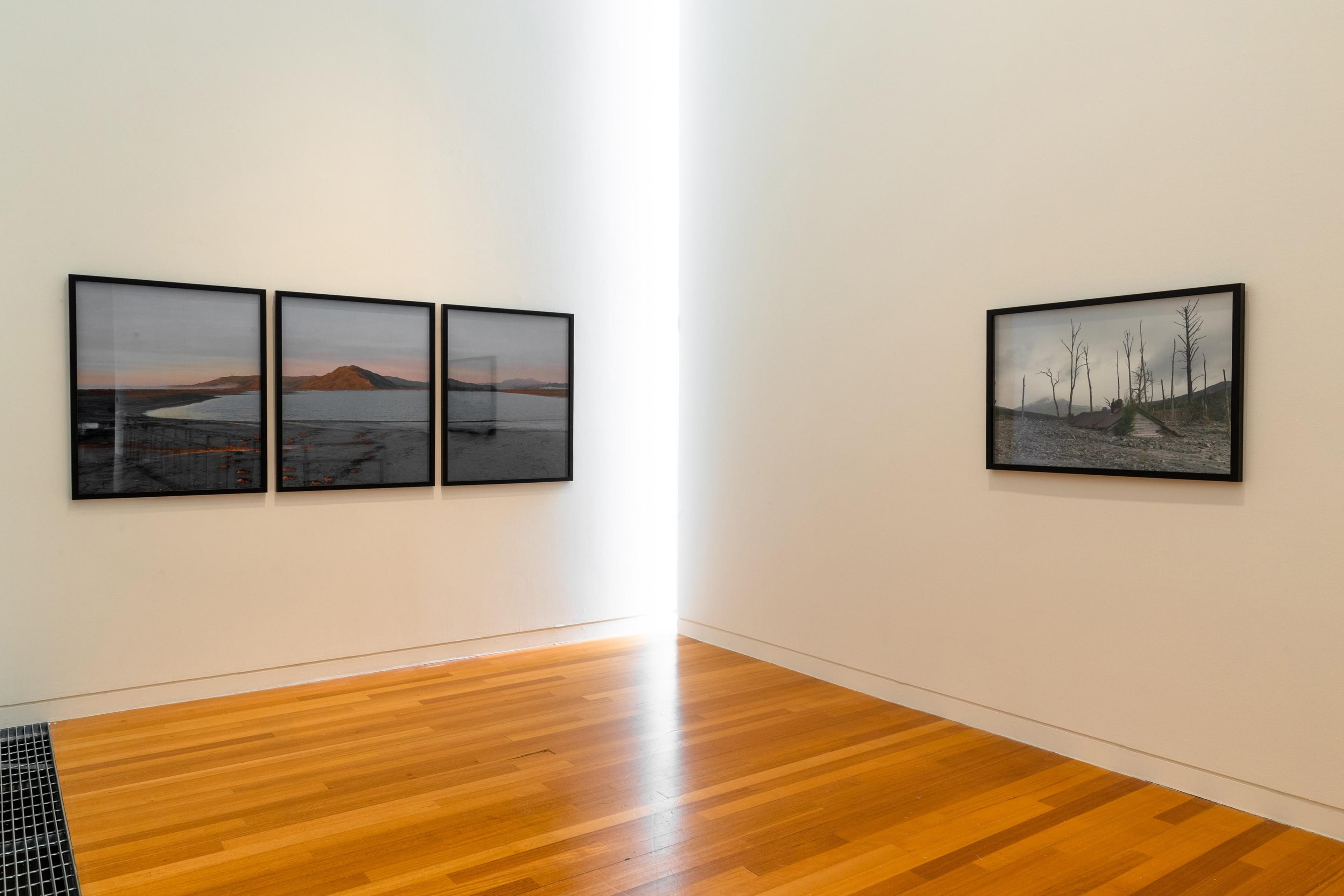 Natalie Robertson, Tera te haeata e takiri ana mai! Behold the first light of dawn! (Waiapu Ngutu Awa triptych, 7th August 2020), 2020, C-type gloss photographic prints; and Buried house – Barton’s Gully (Mangarārā stream flowing into Waiorongomai river) , 2018, C-type gloss photographic print. Courtesy of the artist. Installation view, Tēnei Ao Tūroa – This Enduring World, Te Pātaka Toi Adam Art Gallery, Victoria University Wellington. Photo: Ted Whitaker