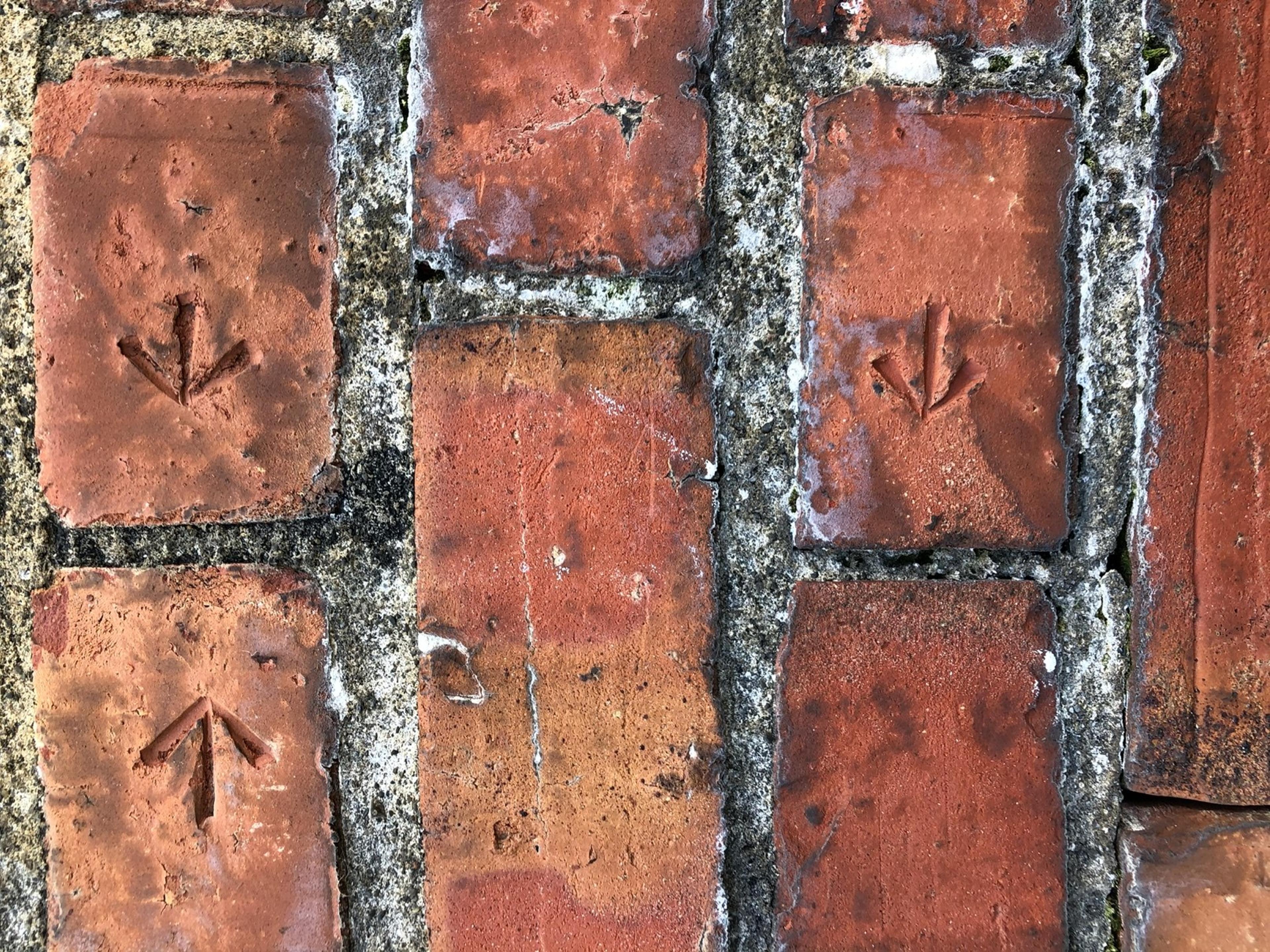 Detail of brick wall, arrows directing up and down carved into bricks.